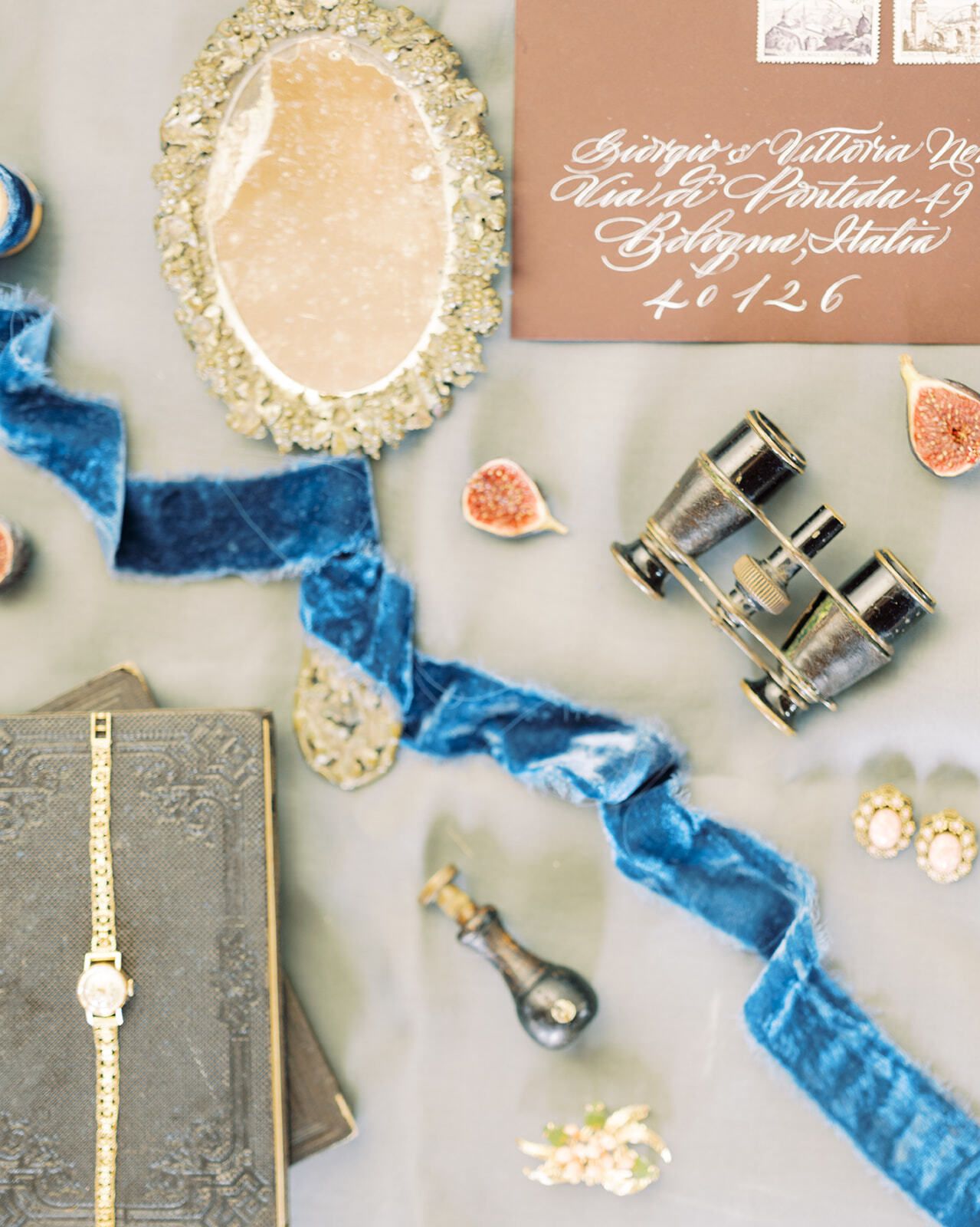 Flat lay con cinta de terciopelo azul, un reloj antiguo y gemelos de teatro