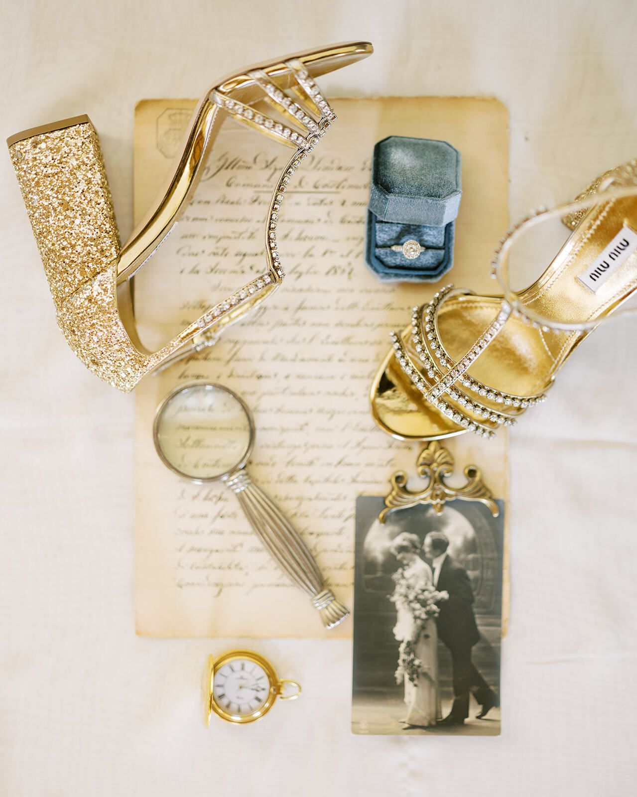 Tacones dorados, un estuche de anillo y una foto antigua sobre una carta de amor