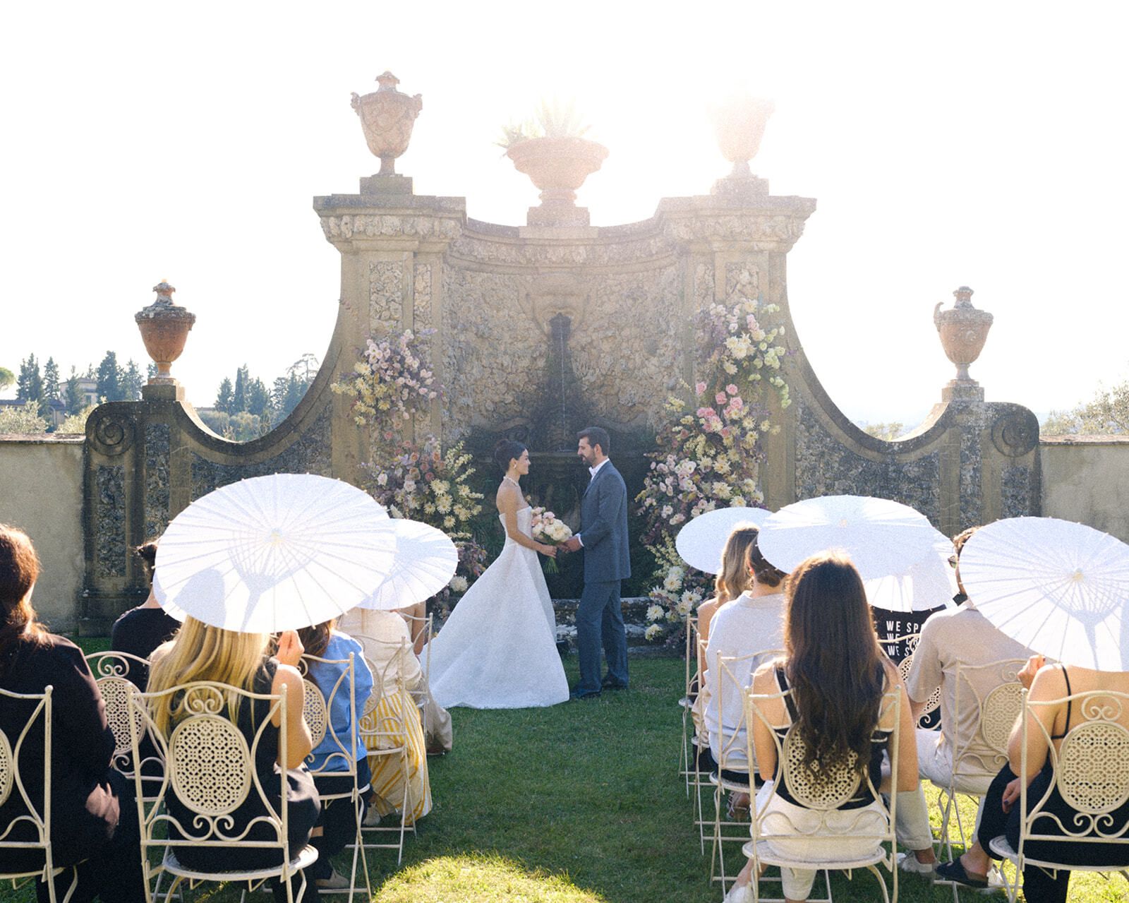 Invitados con sombrillas blancas en una ceremonia en el jardín, Toscana
