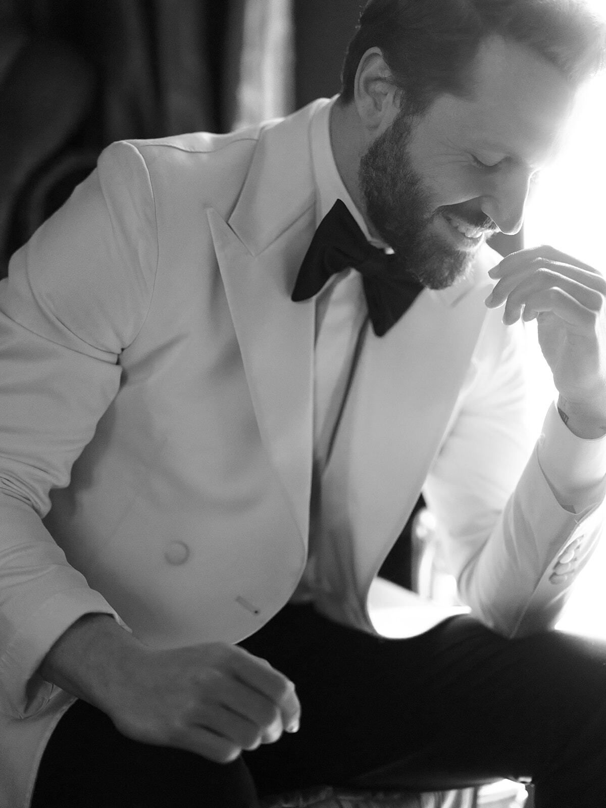 Retrato en blanco y negro de un novio con chaqueta de esmoquin blanca