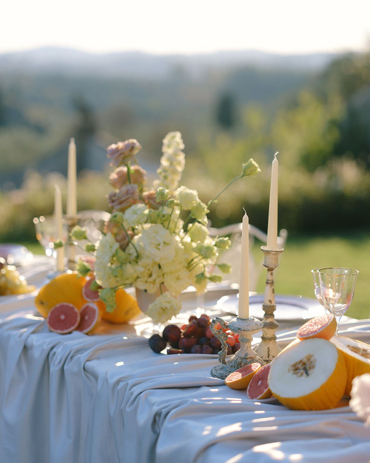 Mesa con fruta y velas y las colinas de la Toscana detrás