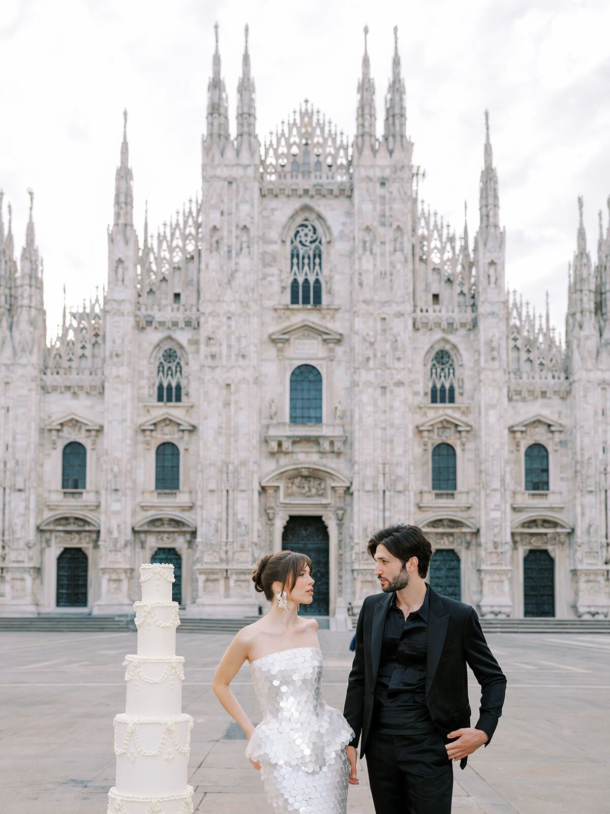 Couple with a white tiered cake in Piazza del Duomo, Milan