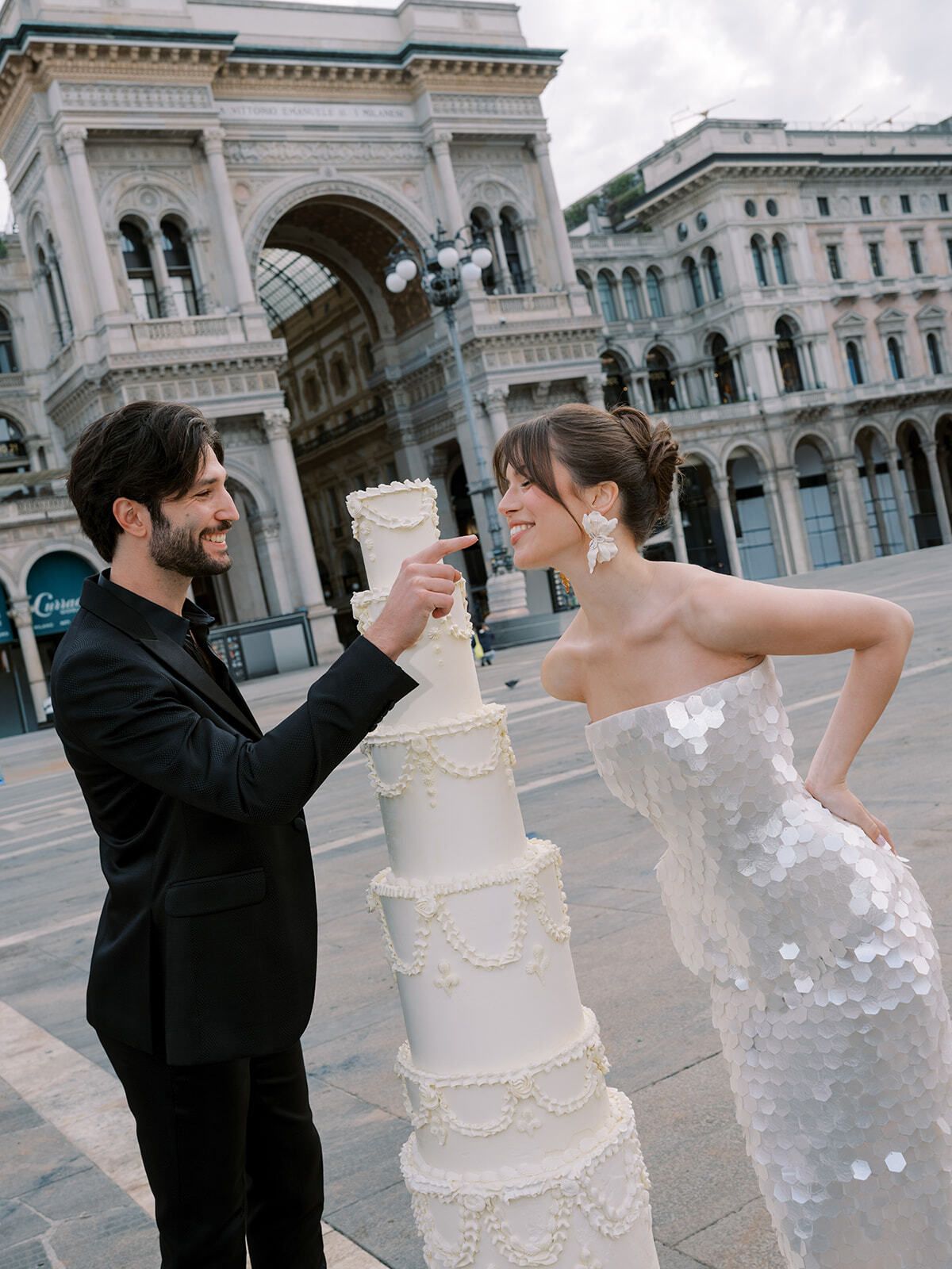 Couple playfully tasting a tiered cake in Piazza del Duomo