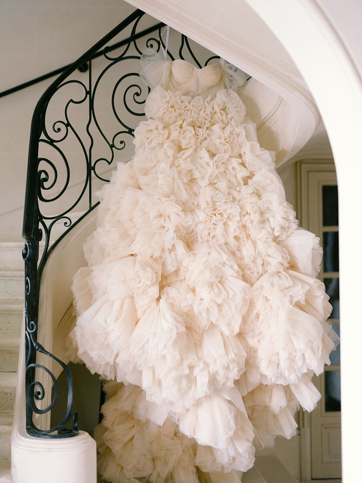 Vestido de novia de volantes rosa empolvado colgado de una escalera de hierro forjado