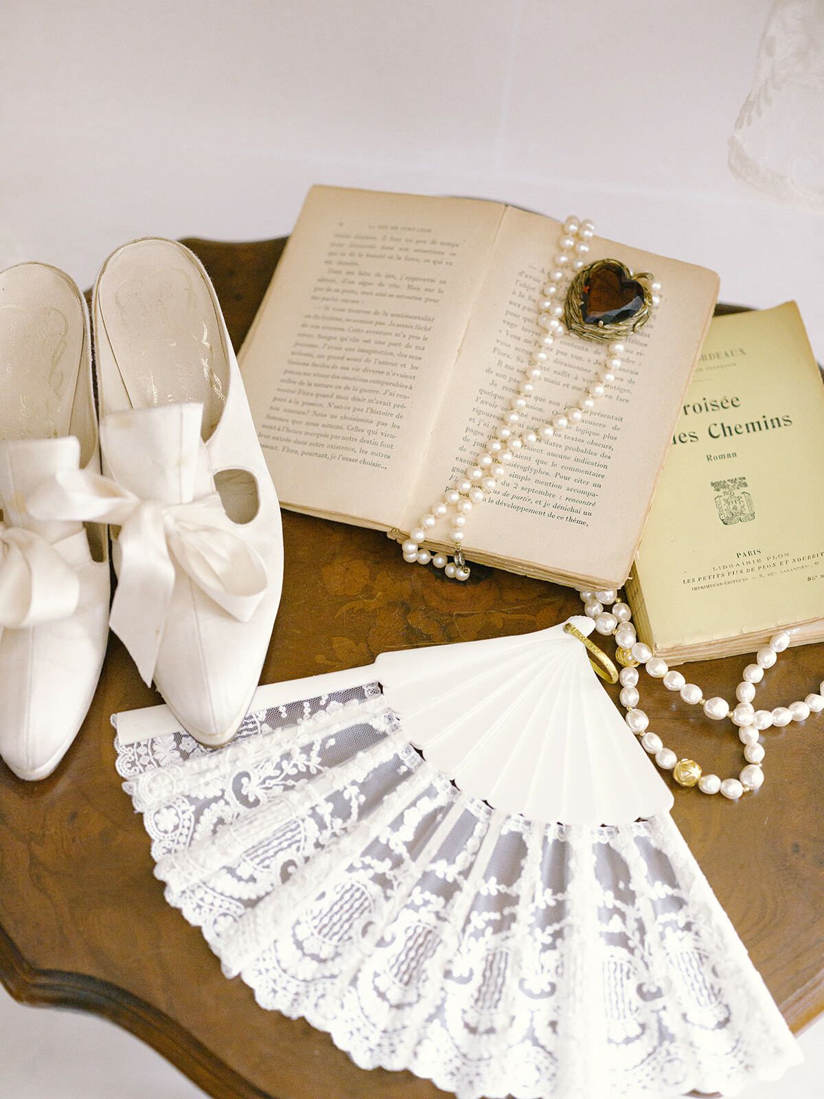 Zapatos de novia, perlas, un abanico de encaje y un libro antiguo