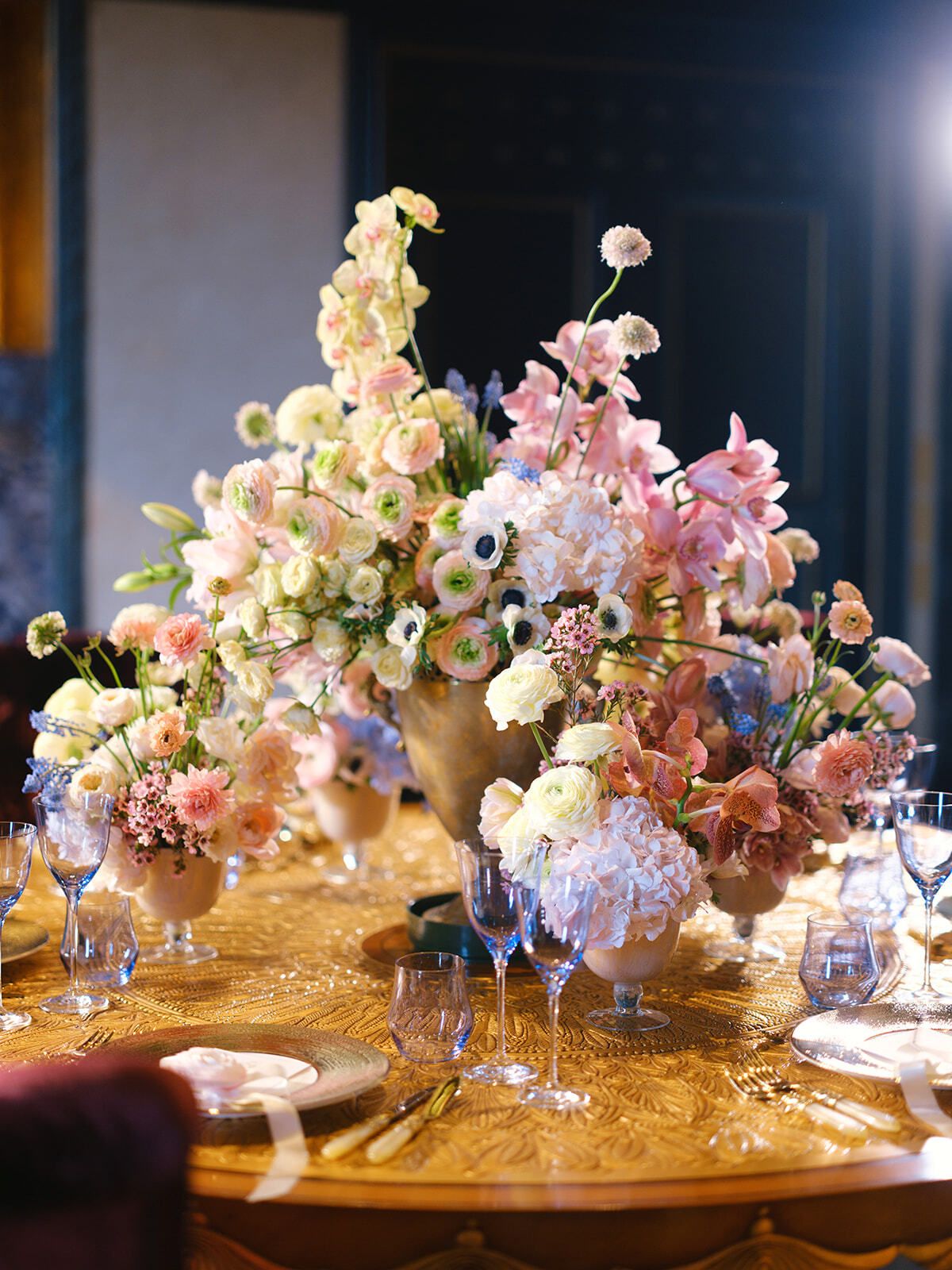 Arreglos florales pastel en una mesa de cena dorada