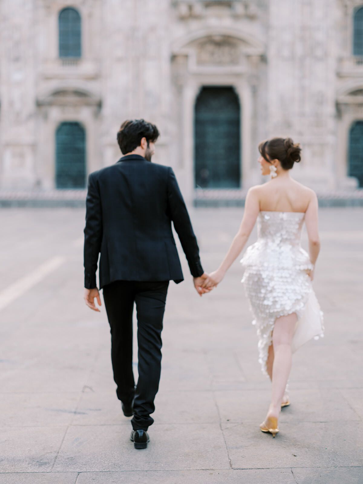 Couple walking hand in hand toward Milan Cathedral