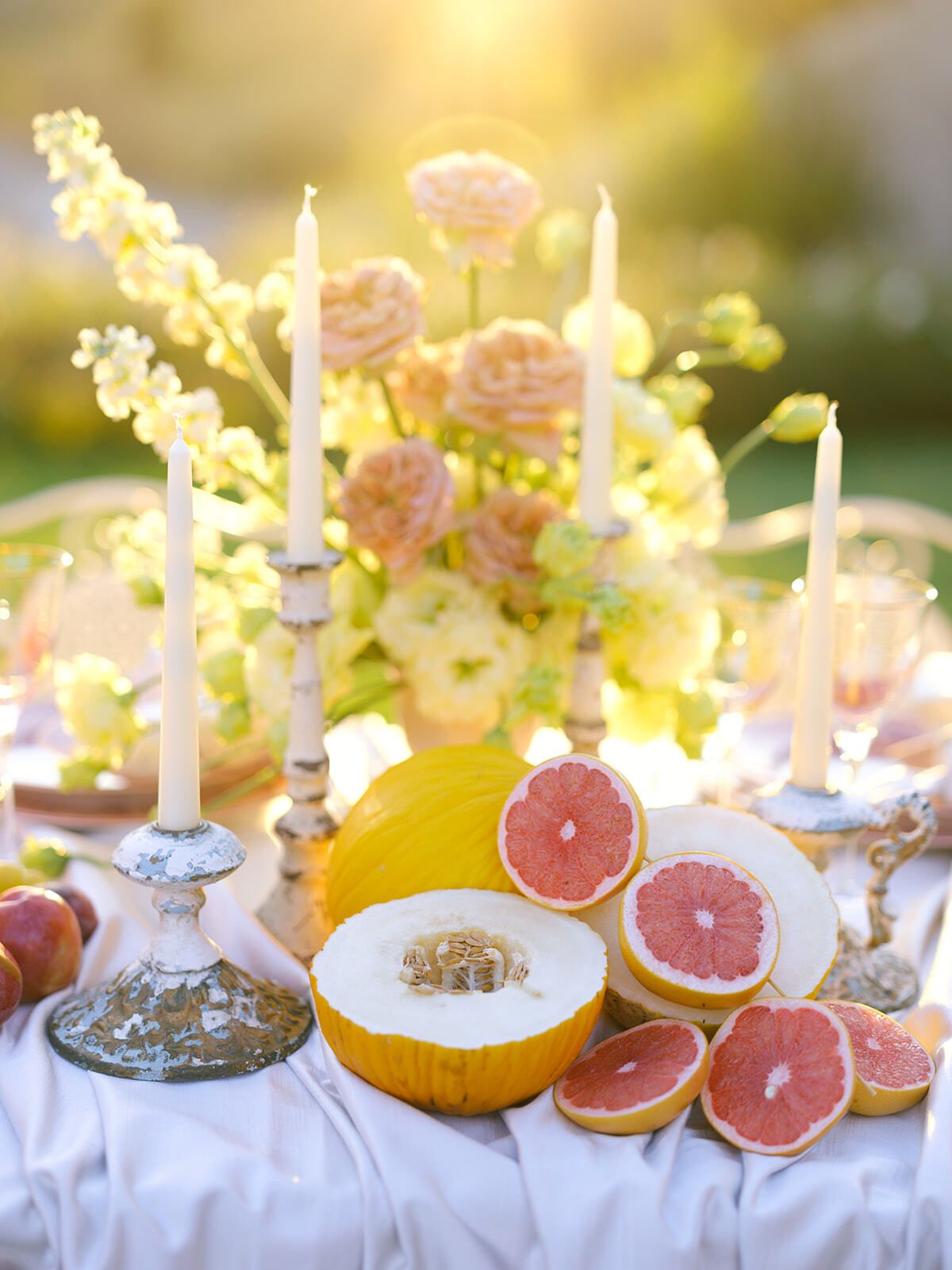 Mesa decorada con pomelo, melón y flores color melocotón