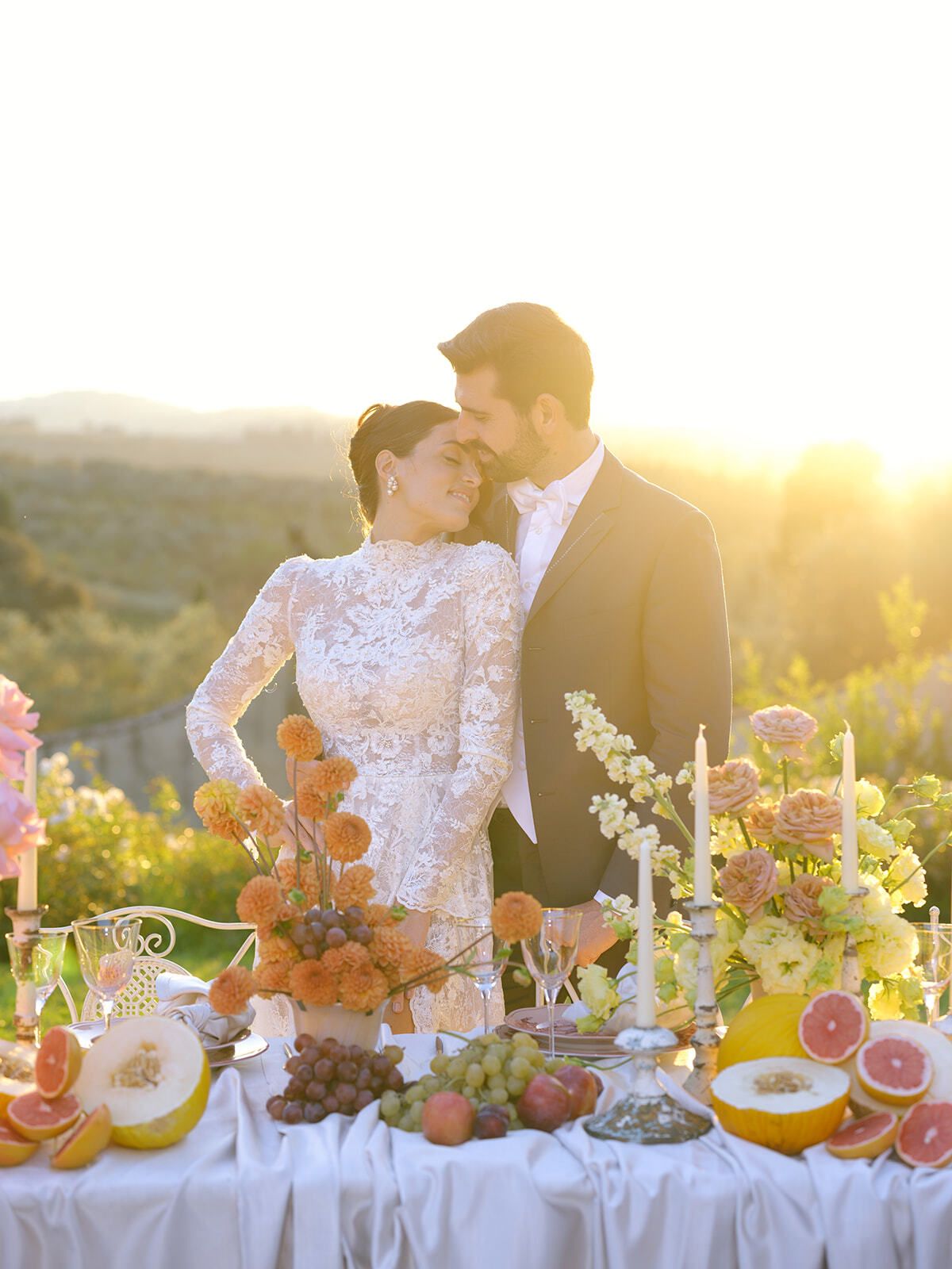 Novios a la hora dorada tras la mesa de fruta
