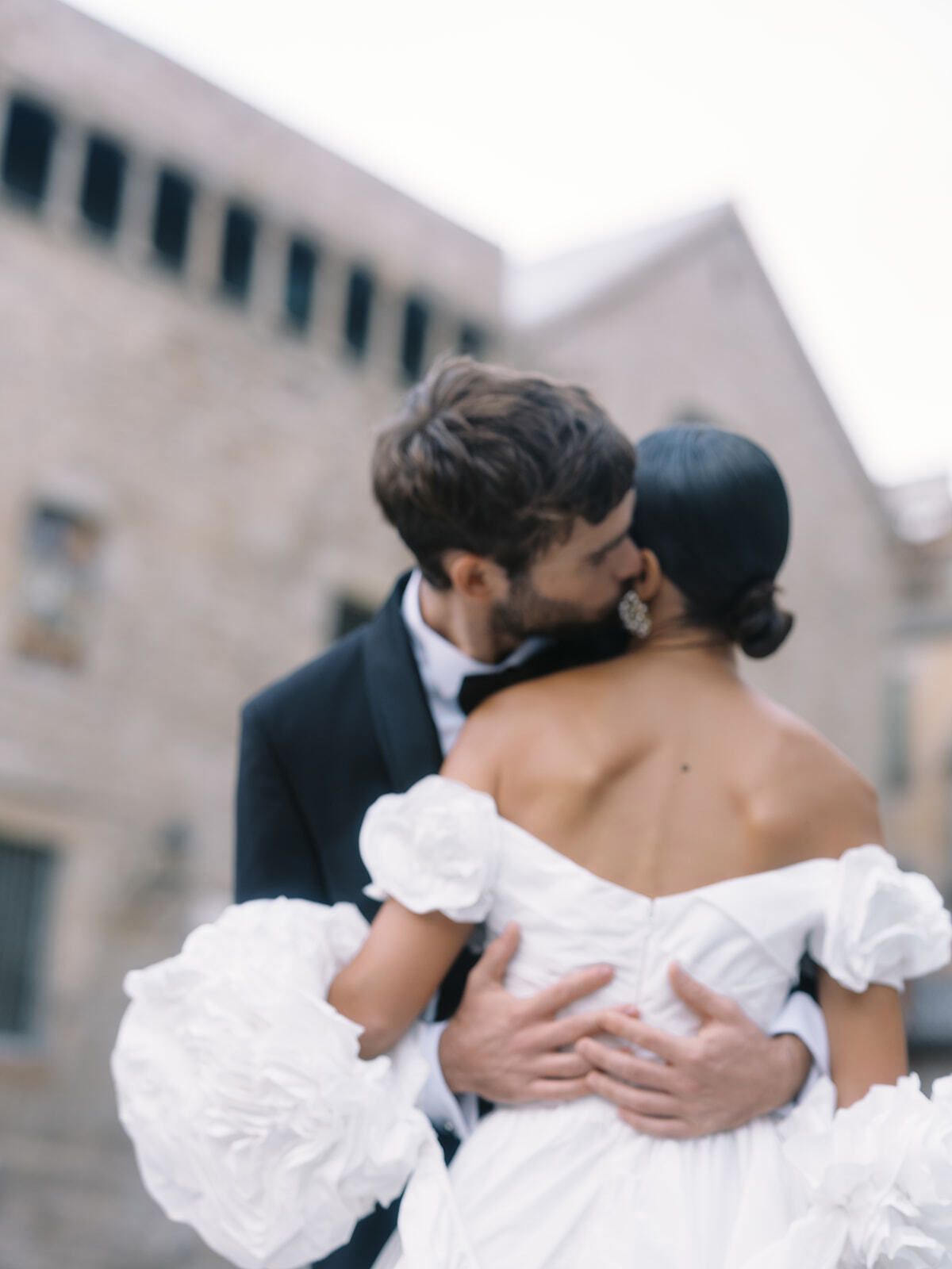 Novio besando a la novia, con vestido de mangas abullonadas, en Barcelona