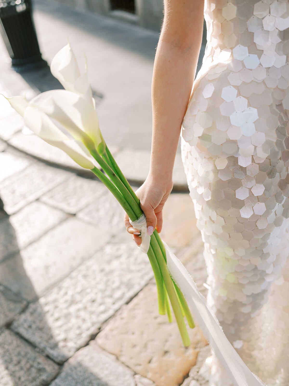 Calla lilies held against a sequined dress