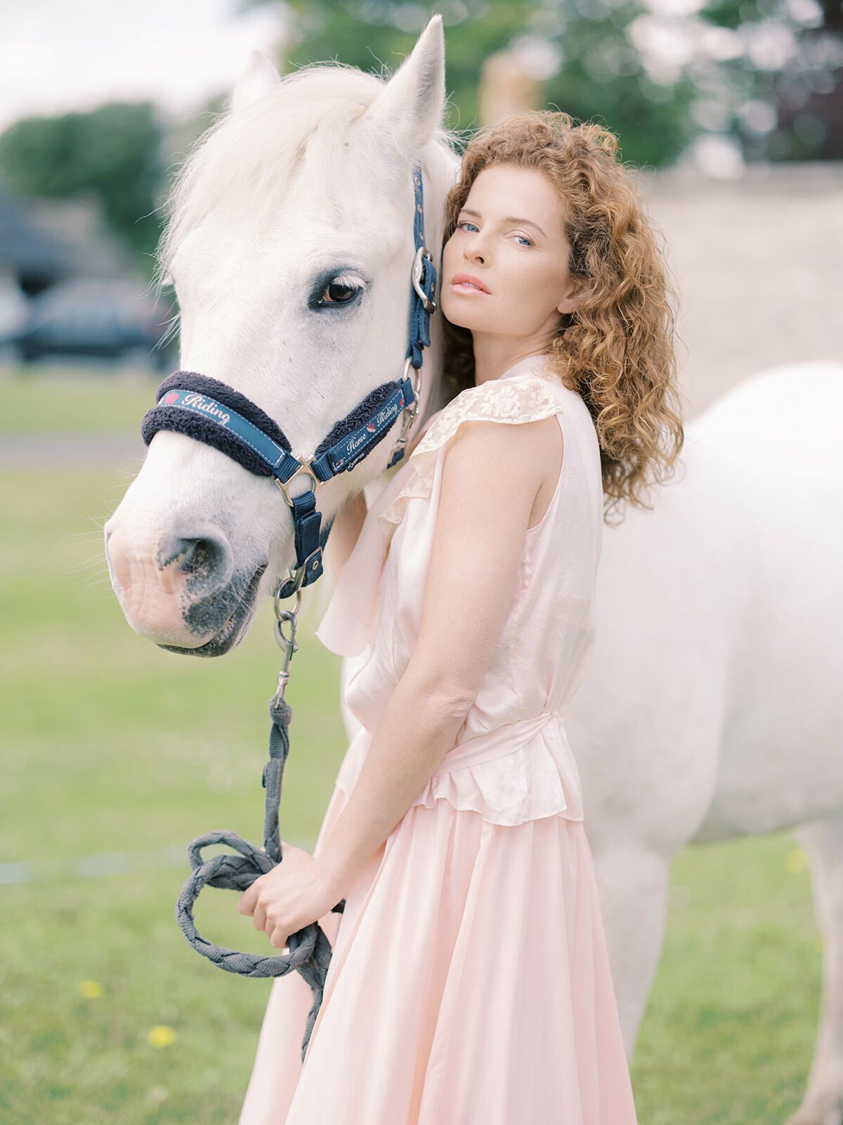 Novia pelirroja de rosa empolvado con un caballo blanco