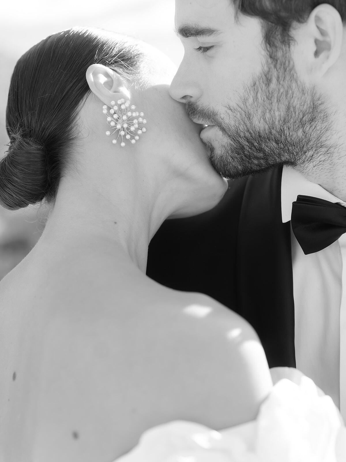 Primer plano en blanco y negro del novio besando el cuello de la novia