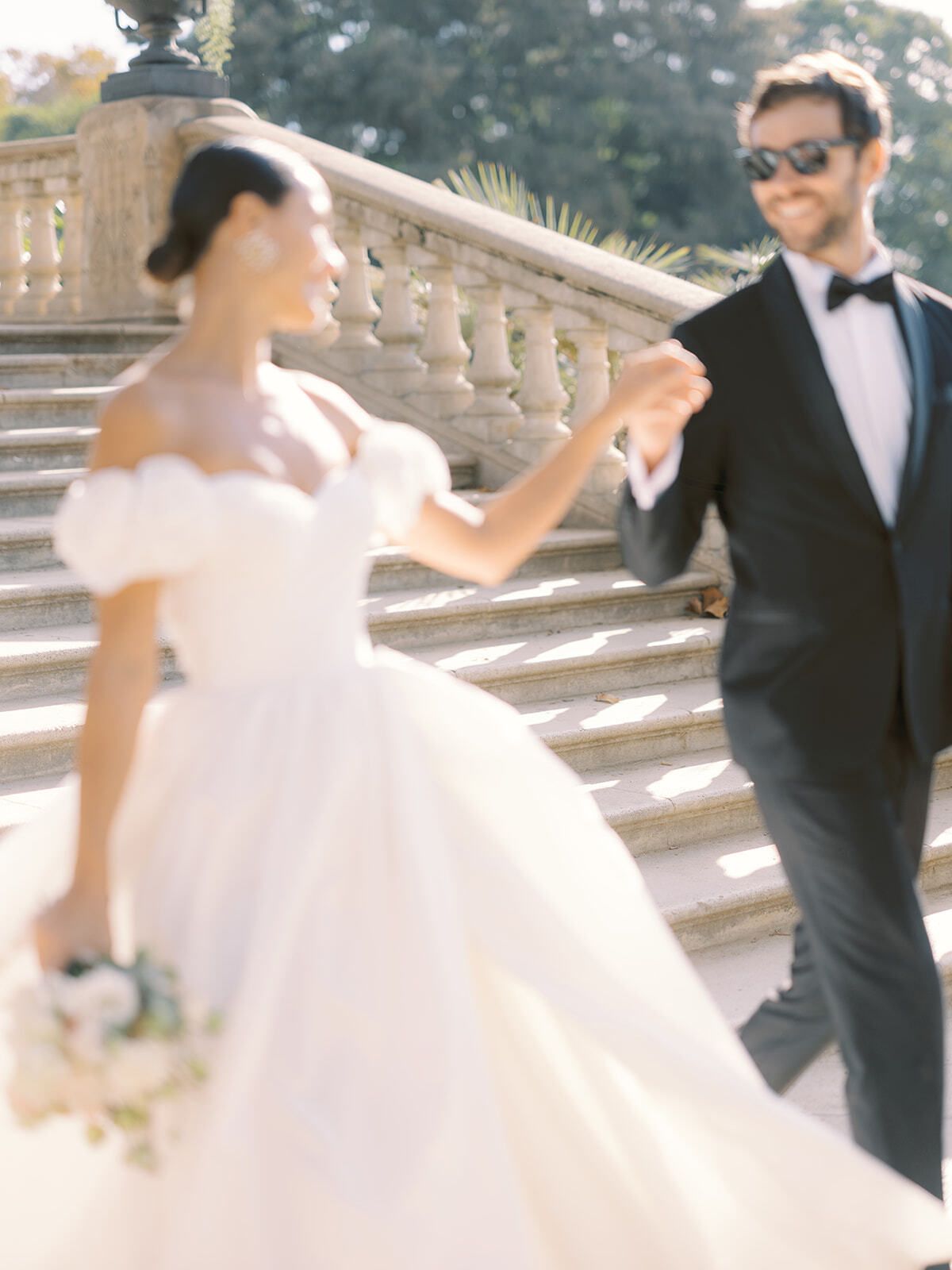 Novios riendo en una gran escalinata de piedra en Barcelona