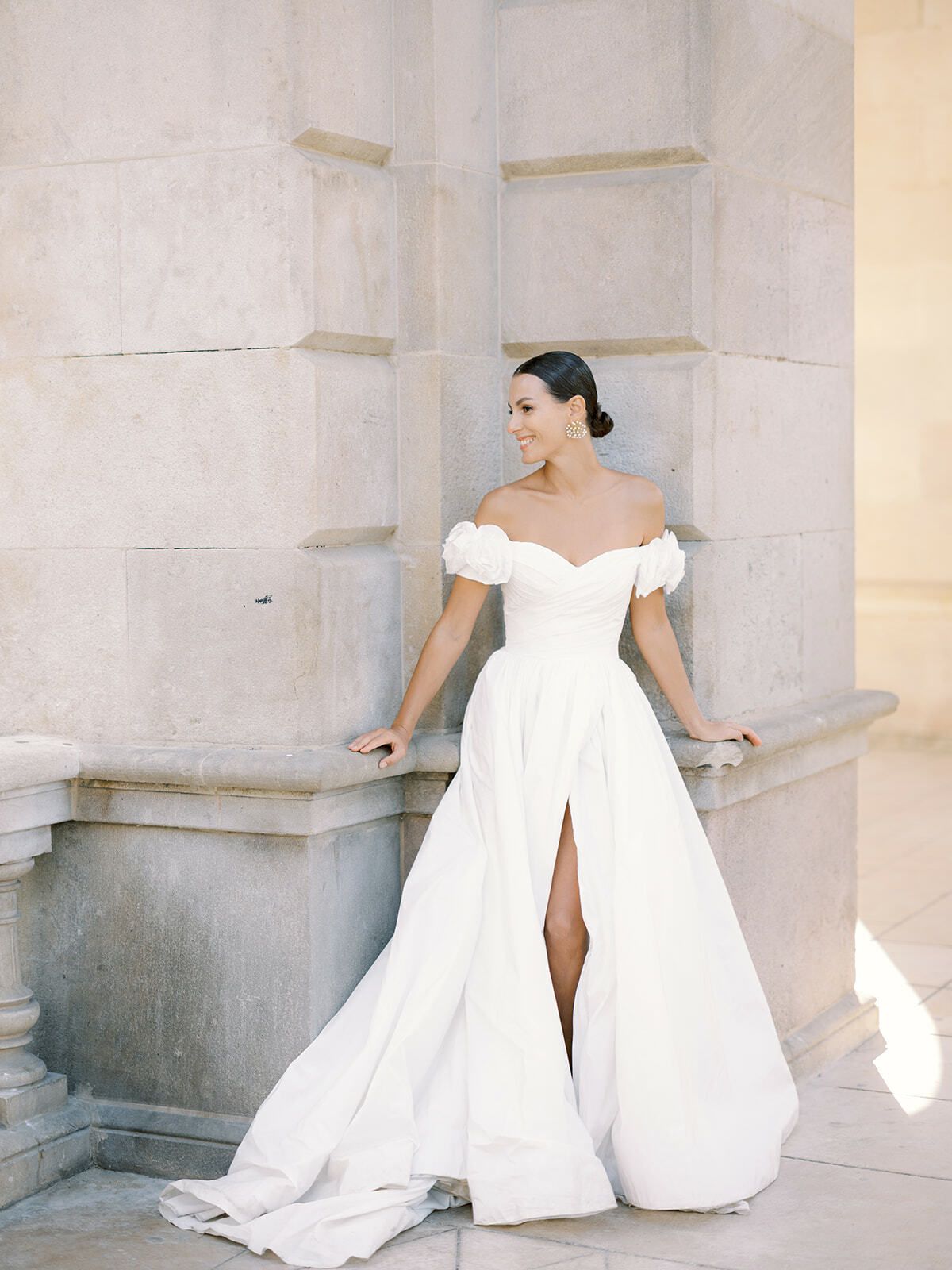 Braut in schulterfreiem Kleid lehnt an einer Steinbalustrade, Barcelona