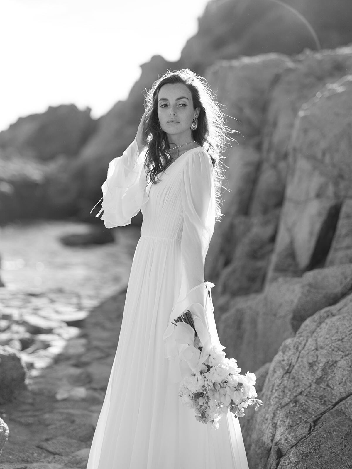 Retrato en blanco y negro de una novia en las rocas de la costa