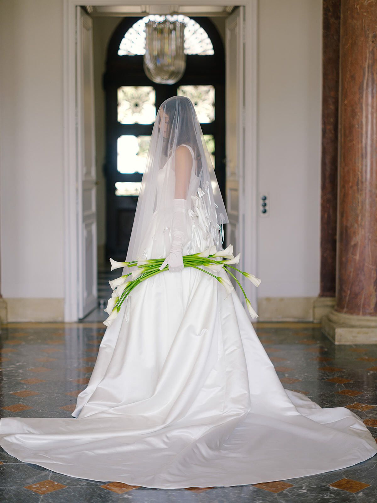 Novia con velo catedral y calas en un salón del château