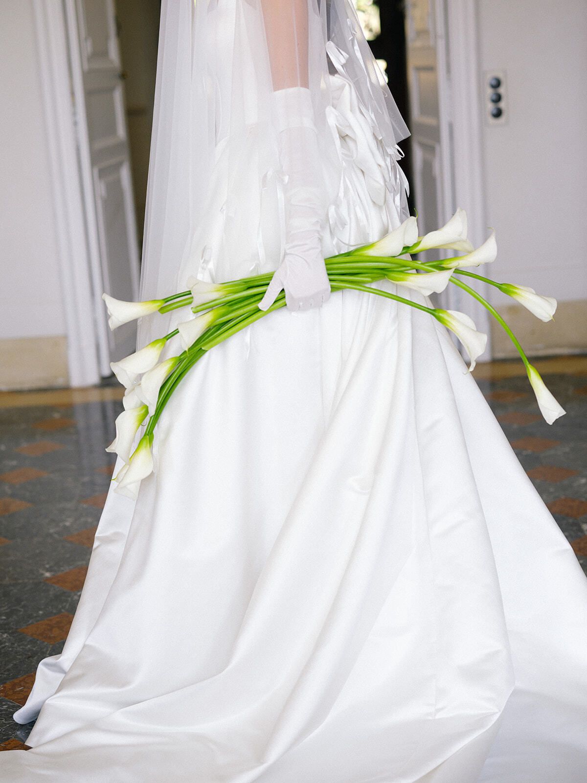 Calla-Lilien hinter einem Brautkleid aus Satin
