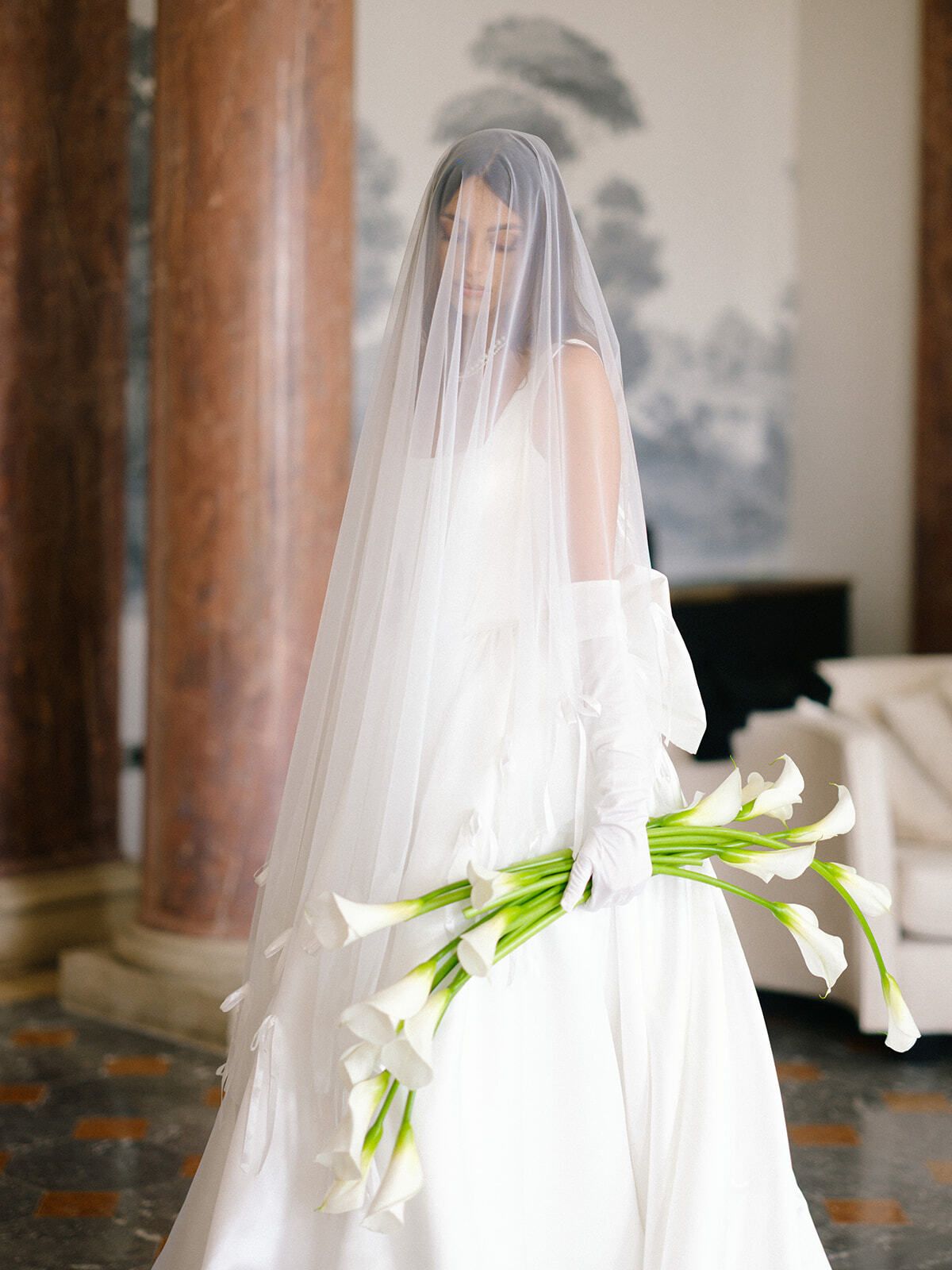 Braut mit Schleier und Calla-Lilien in einem Schlosssalon