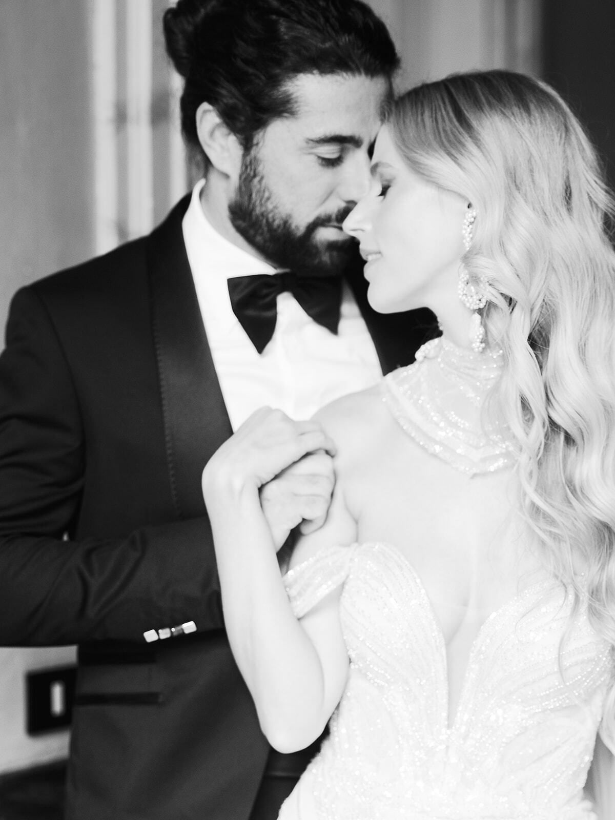Portrait en noir et blanc du marié tenant la main de la mariée