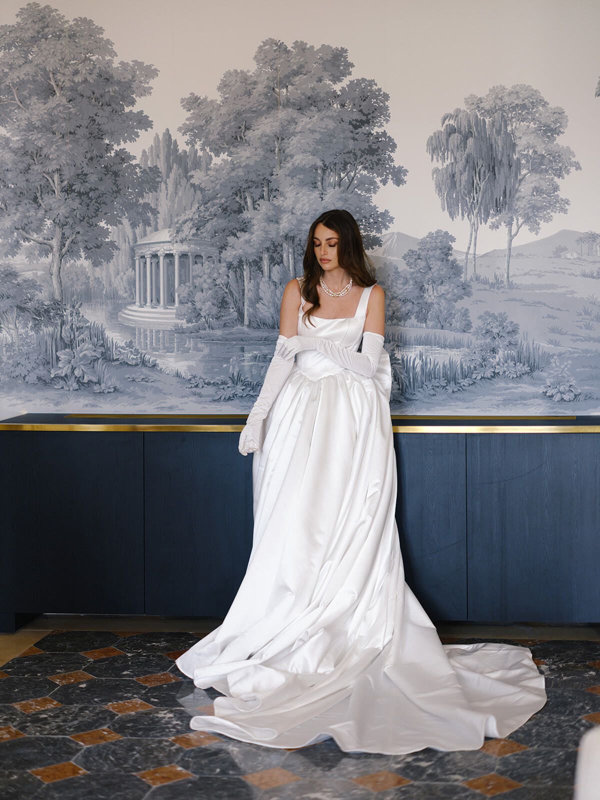 Novia con vestido de satén ante un papel pintado toile