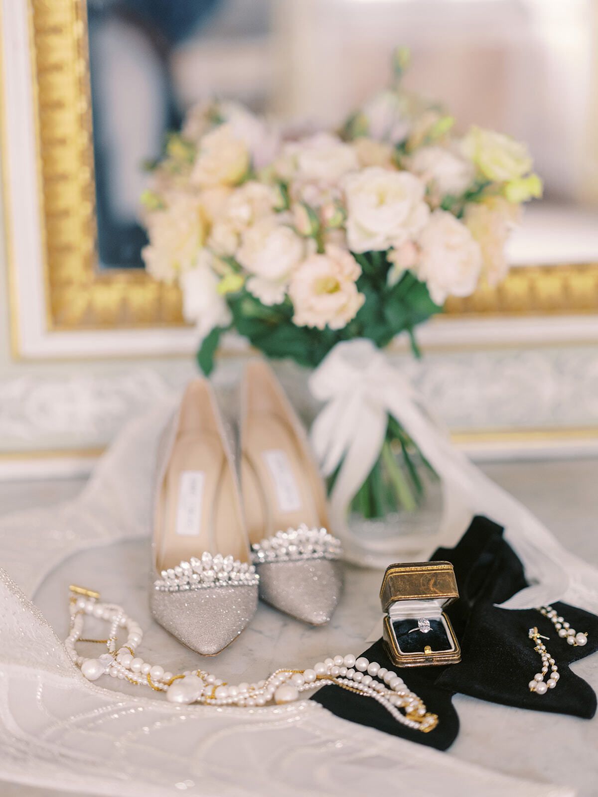Zapatos de tacón, joyas y rosas de novia en una bandeja dorada