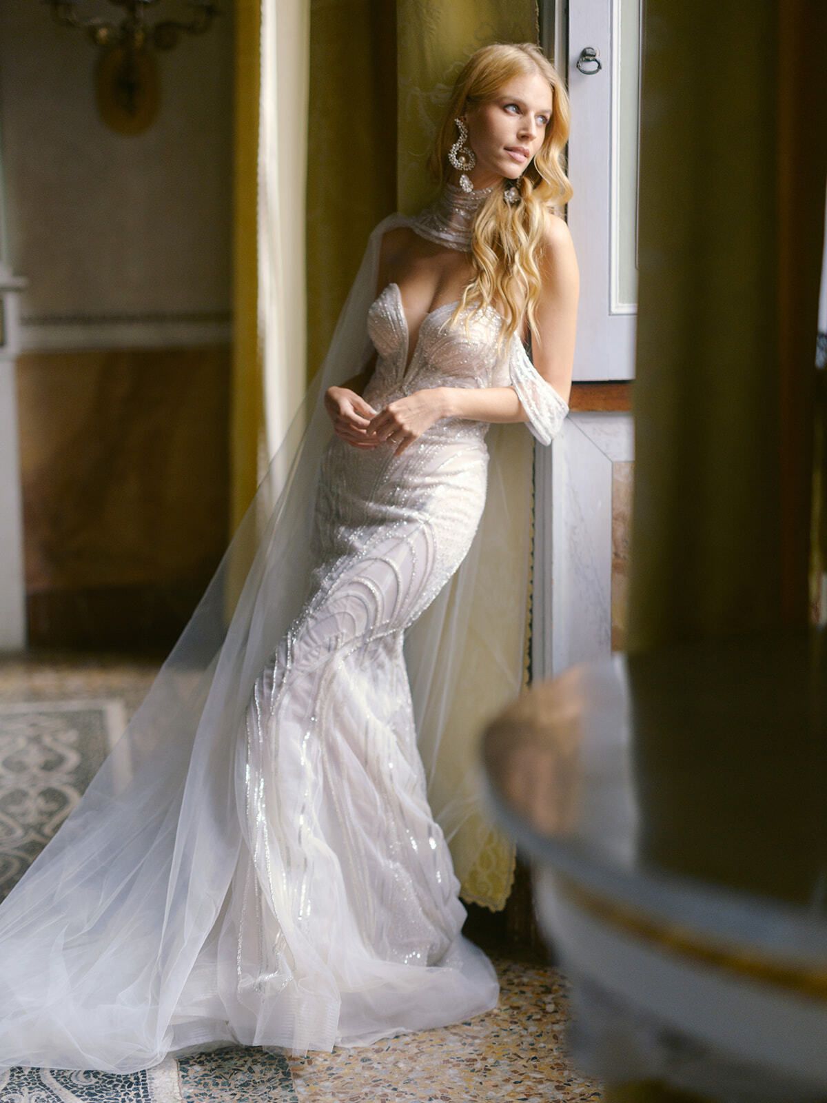 Novia con vestido sirena de encaje y velo largo en un salón de la villa