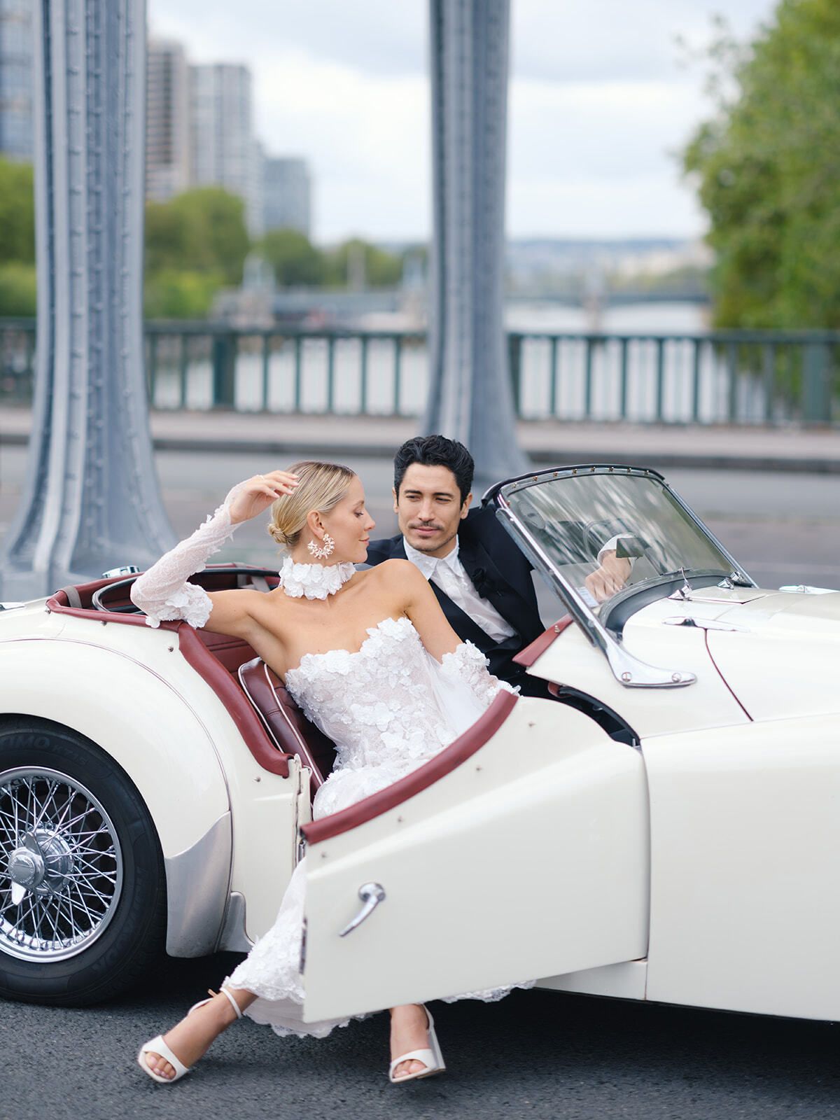 Paar in einem weißen Oldtimer-Cabrio an der Pont de Bir-Hakeim