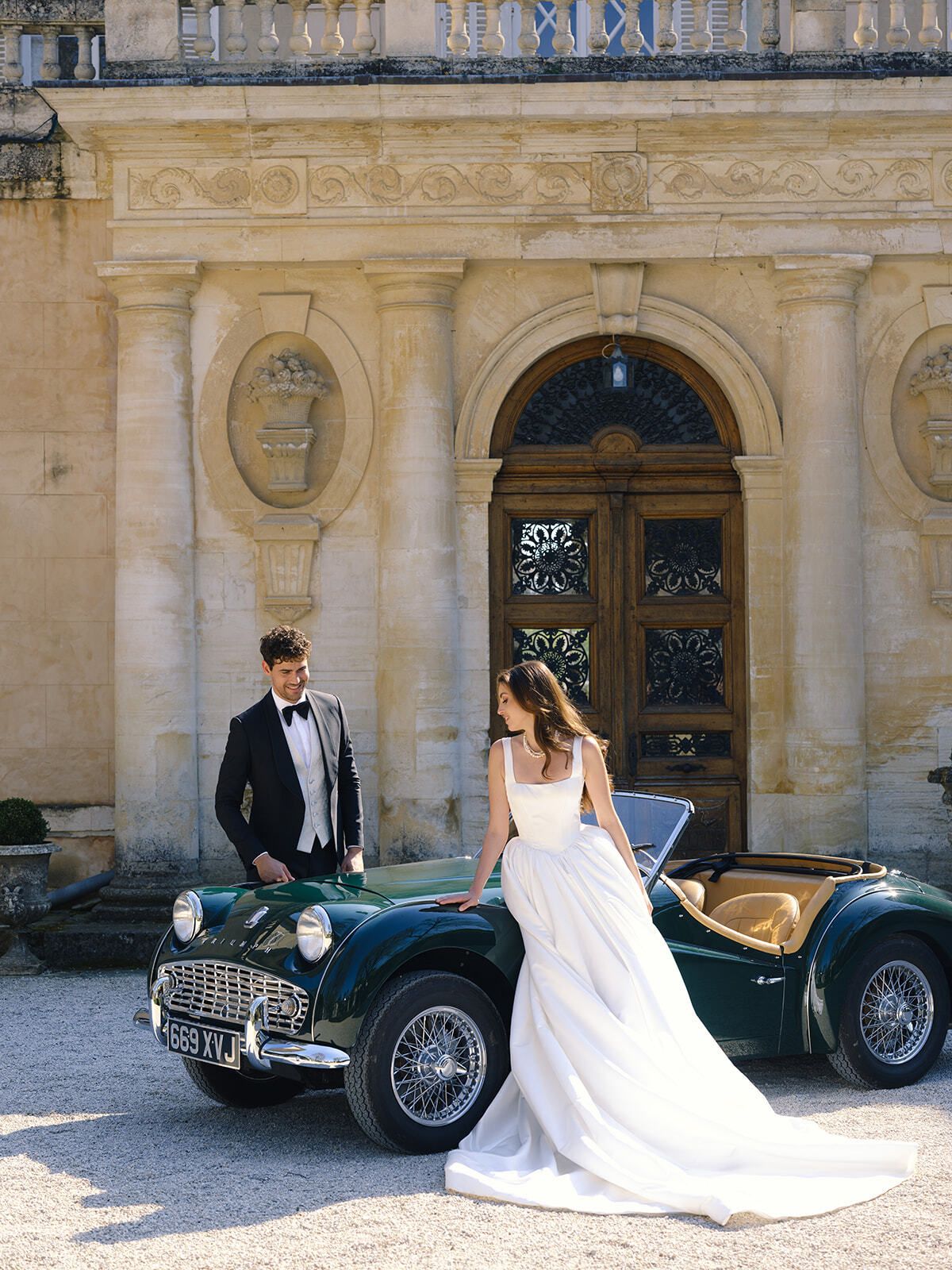 Brautpaar mit einem grünen Oldtimer-Roadster im Château Martinay
