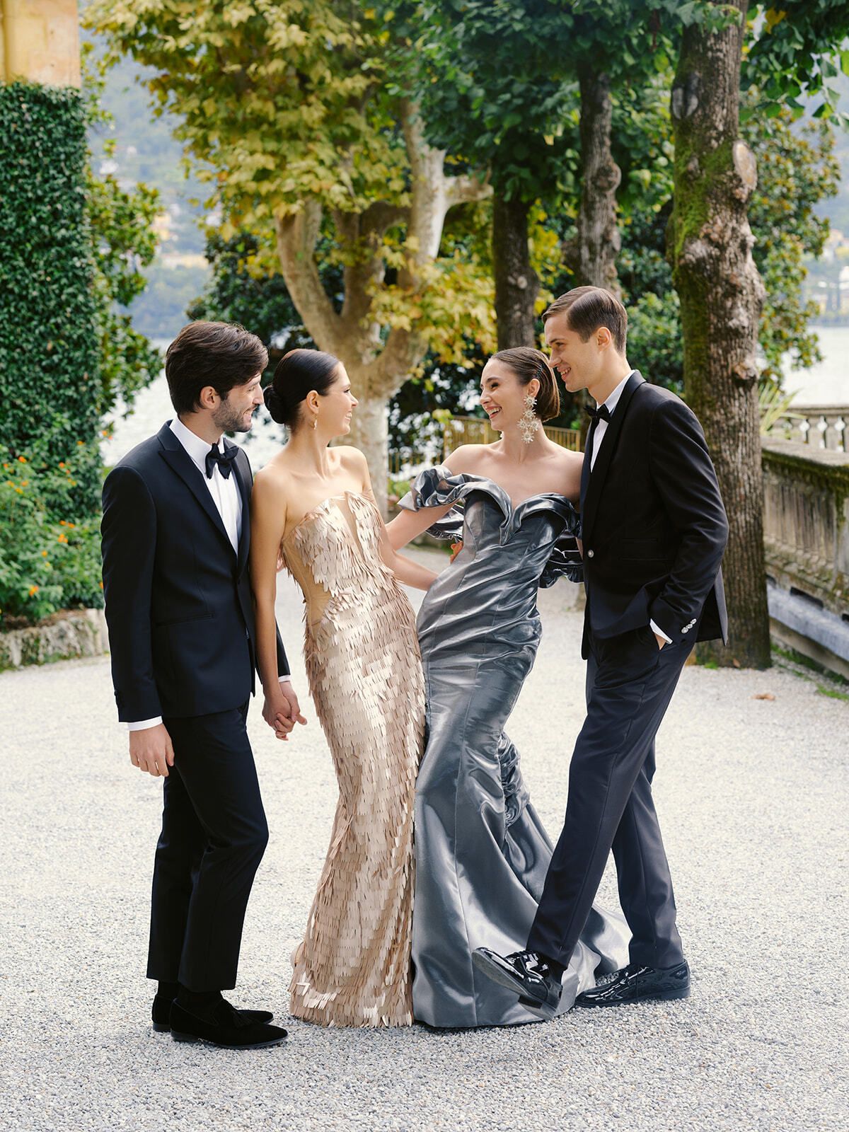 Guests in metallic gowns with partners in the gardens on Lake Como
