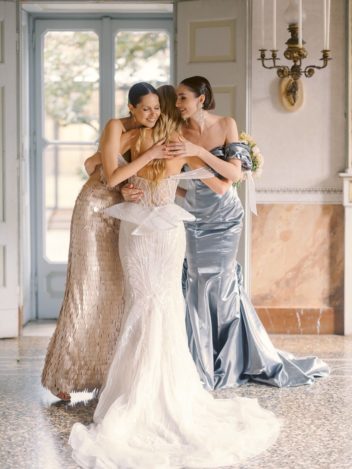 Novia abrazando a sus damas de honor en un salón de la villa