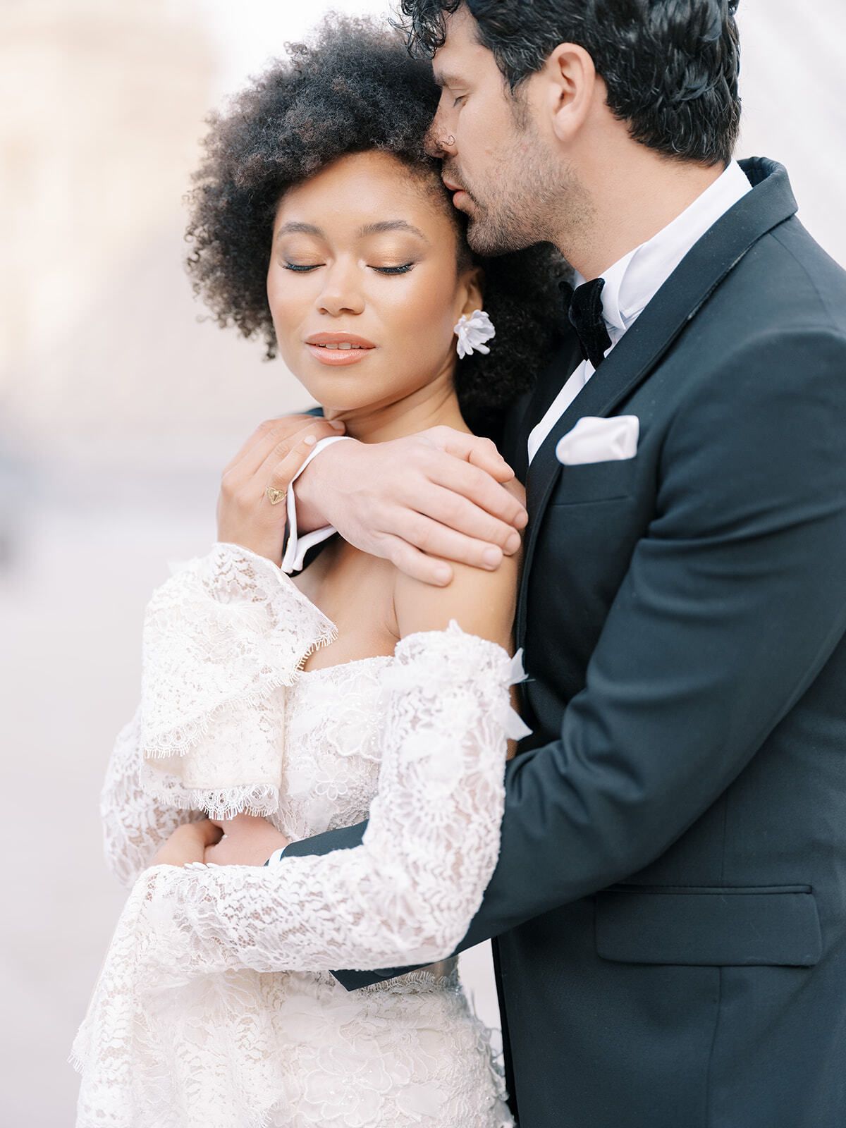 Bräutigam umarmt die Braut im schulterfreien Spitzenkleid, Paris