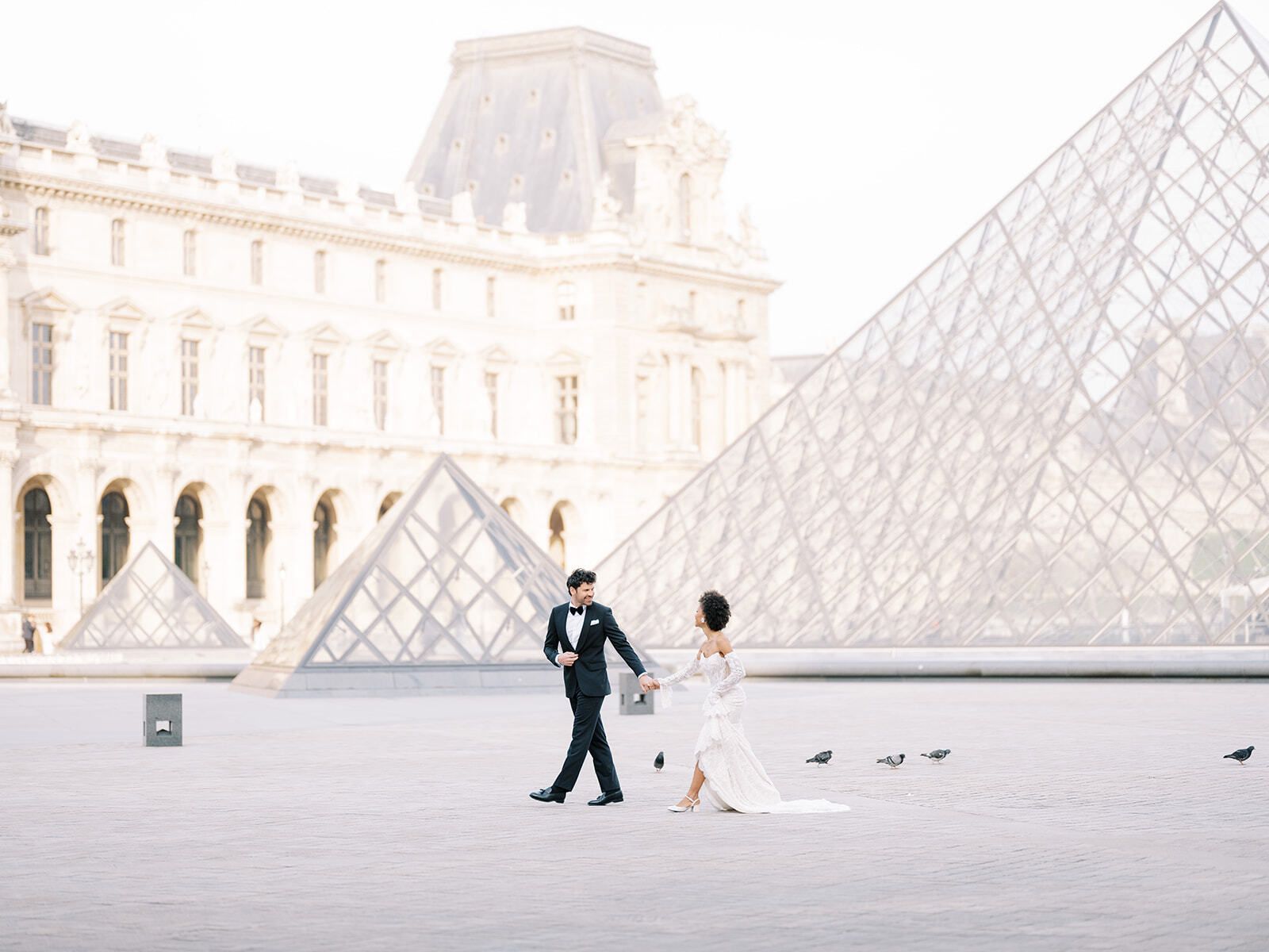 Couple walking across the Louvre courtyard by the Pyramid