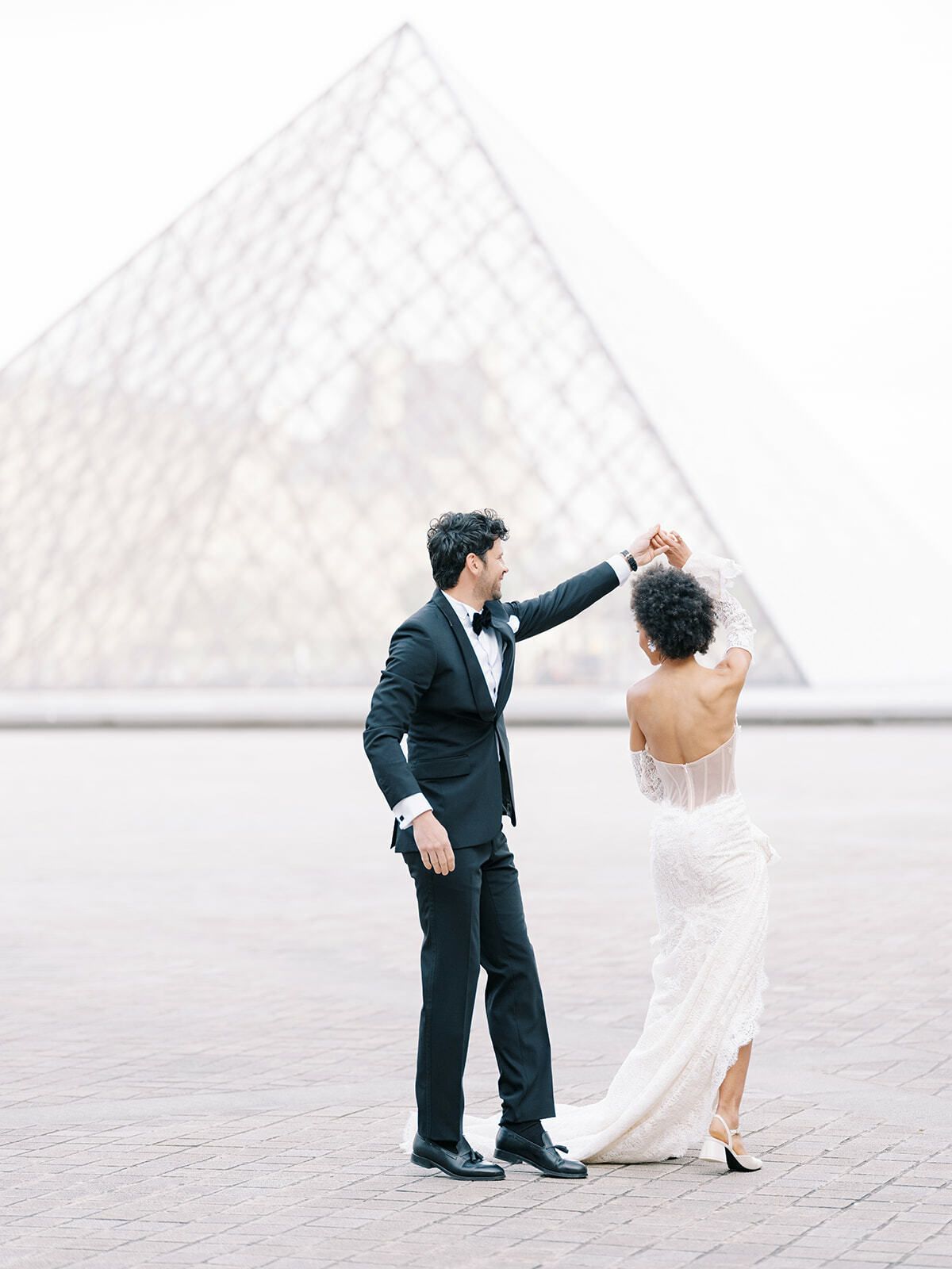 Bräutigam dreht die Braut an der Louvre-Pyramide