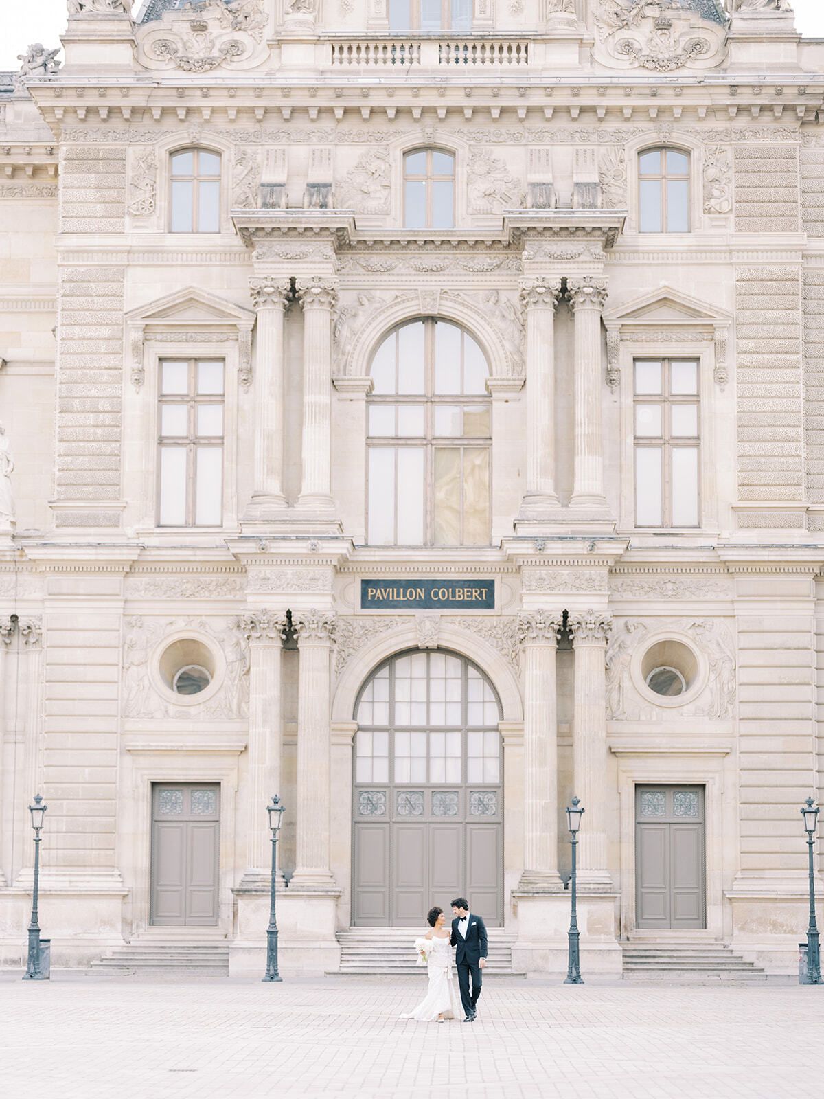 Brautpaar klein vor der Fassade des Louvre