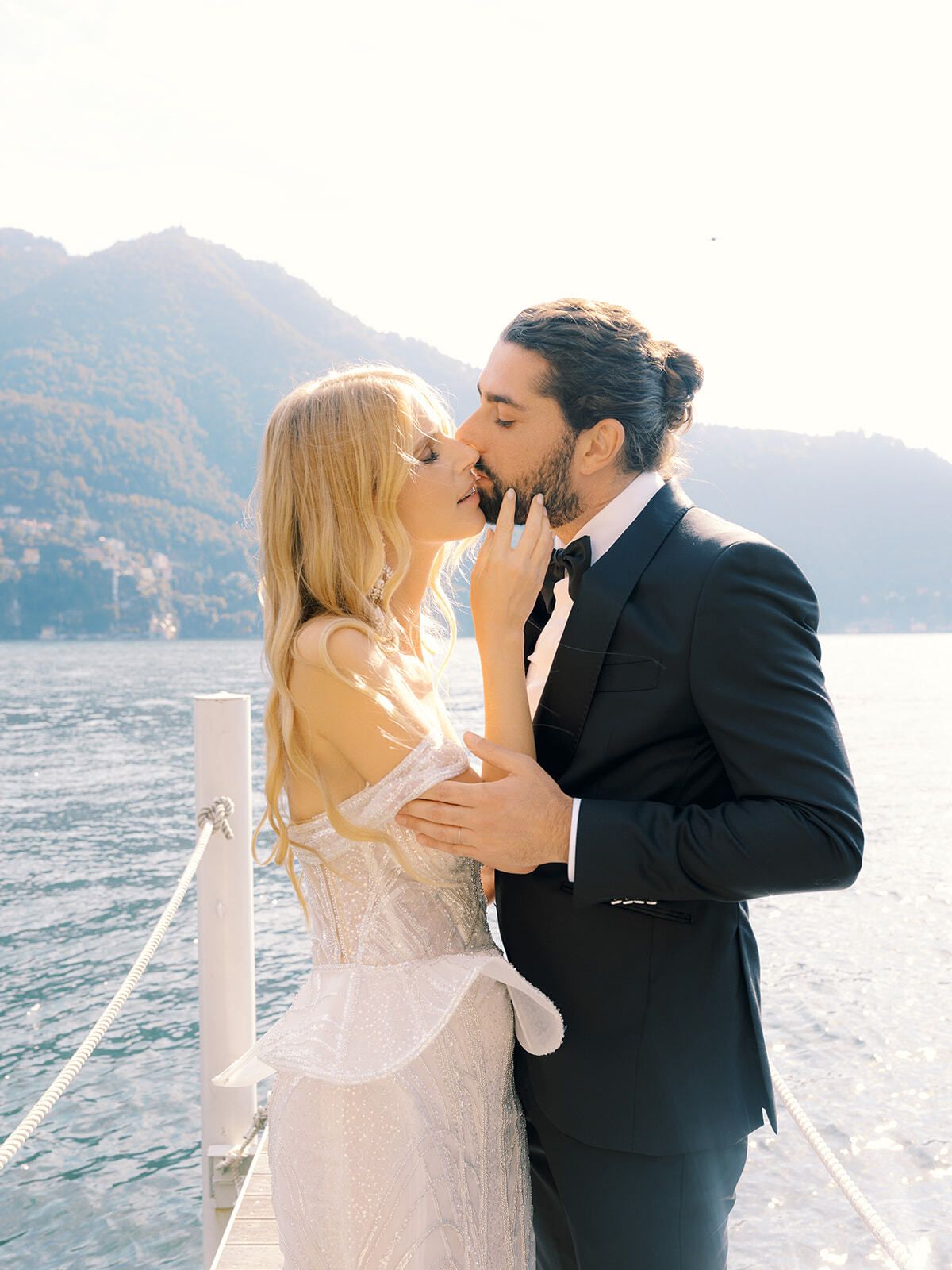 Bride and groom kissing on a jetty on Lake Como