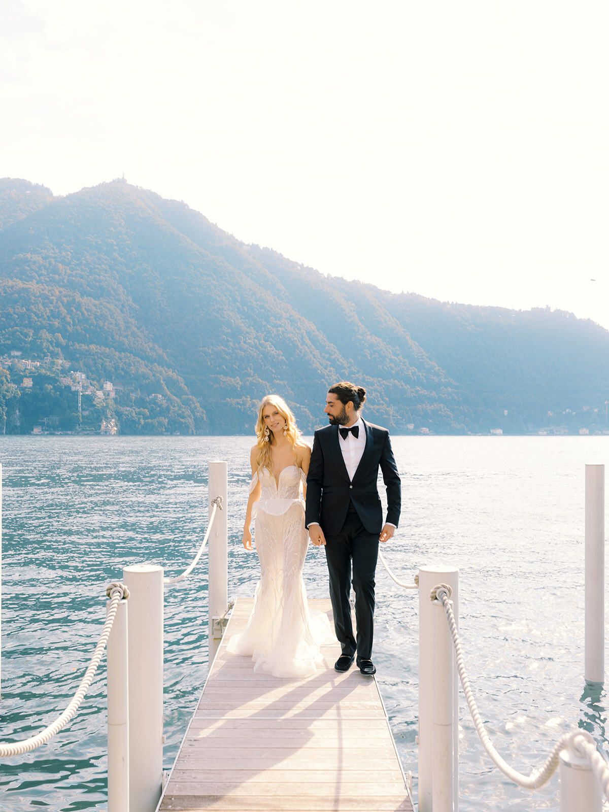 Bride and groom walking on a lakeside jetty, Villa Pizzo