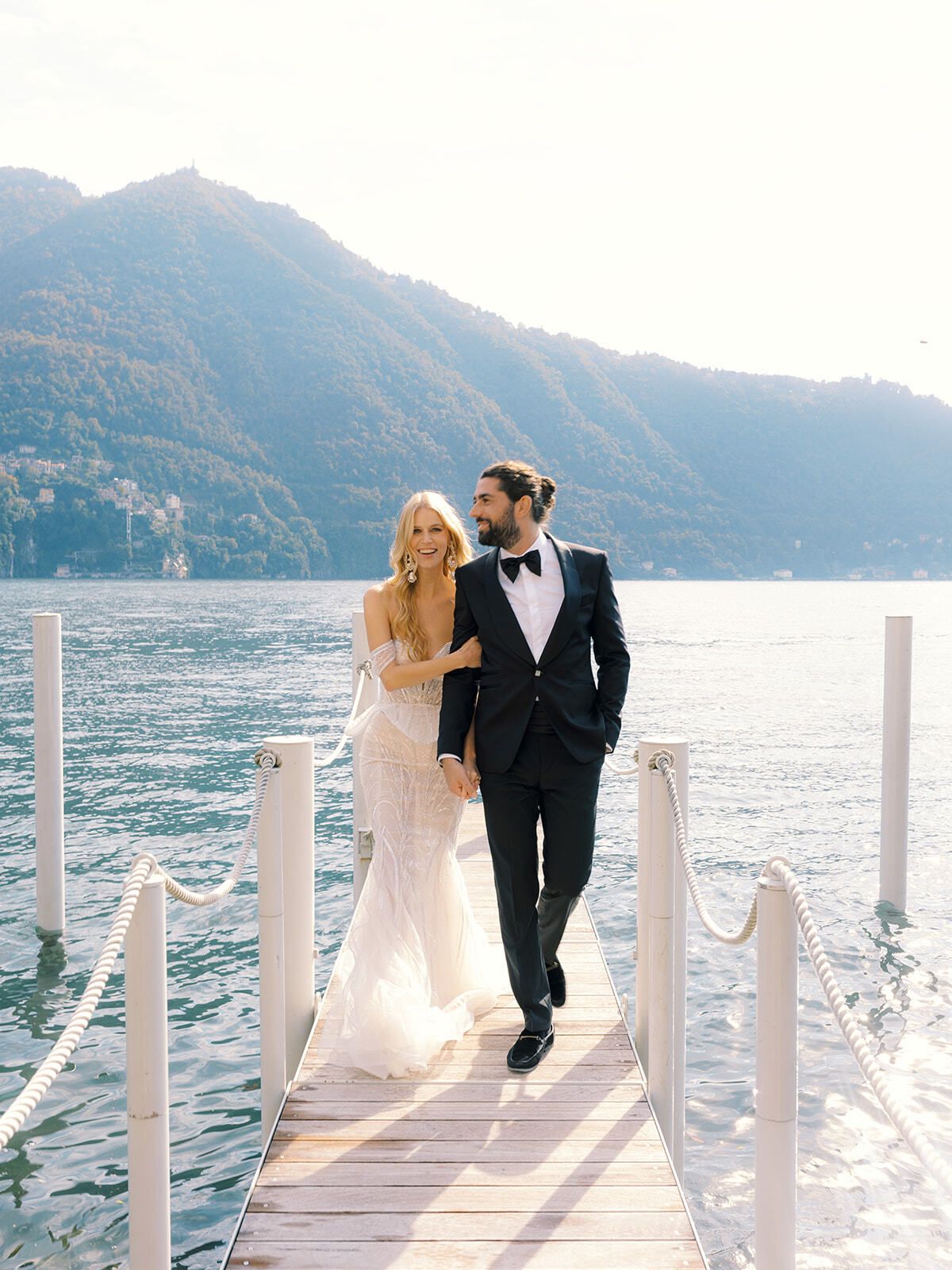 Bride and groom walking along a jetty on Lake Como