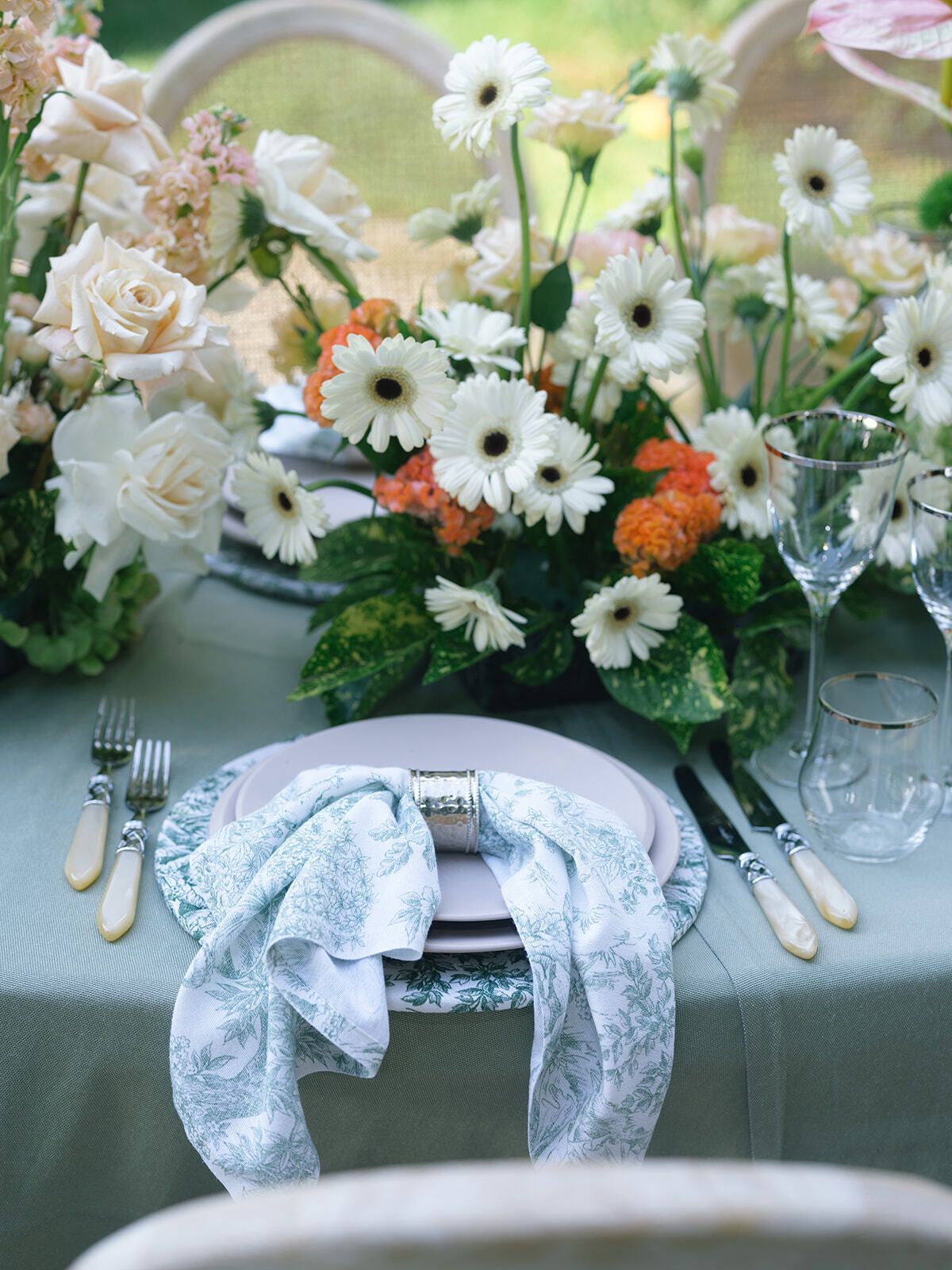 Table setting with daisies, orange blooms and sage linen