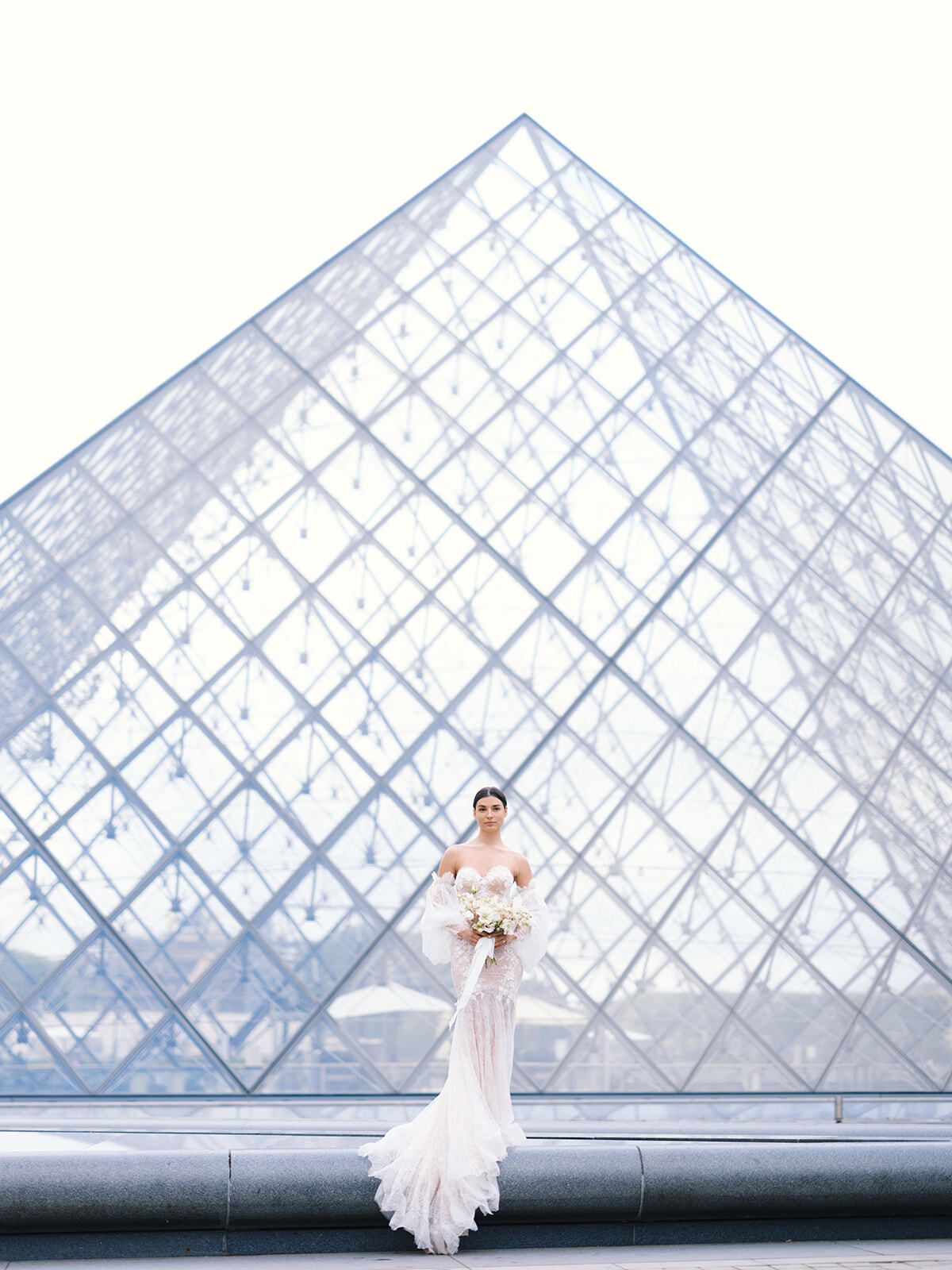 Braut im Meerjungfrauenkleid vor der Louvre-Pyramide