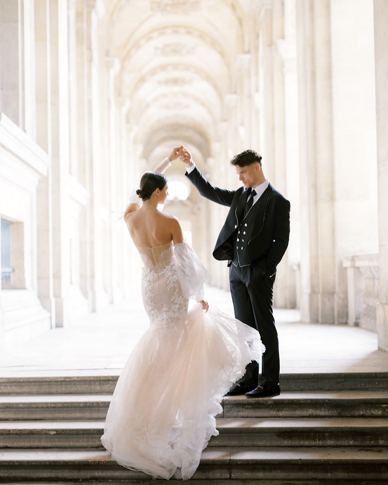Novio haciendo girar a la novia en los escalones de los soportales del Louvre