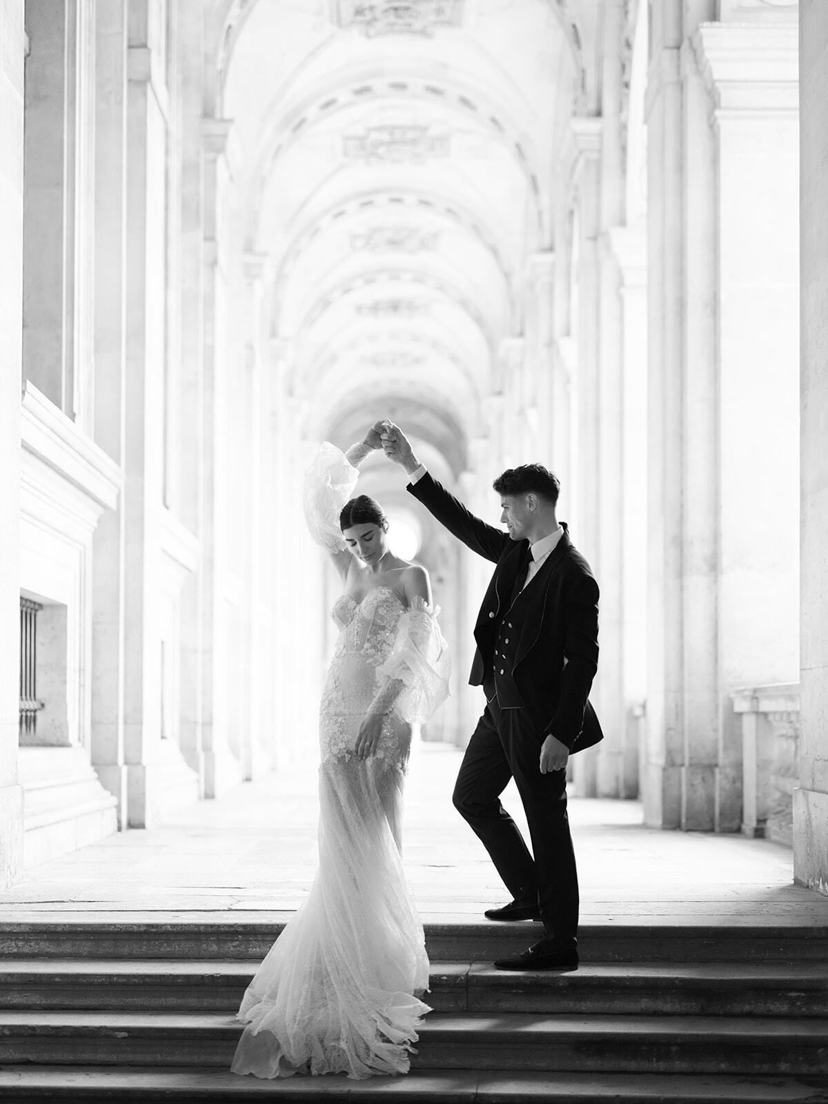 Foto en blanco y negro de una pareja bailando bajo los soportales del Louvre