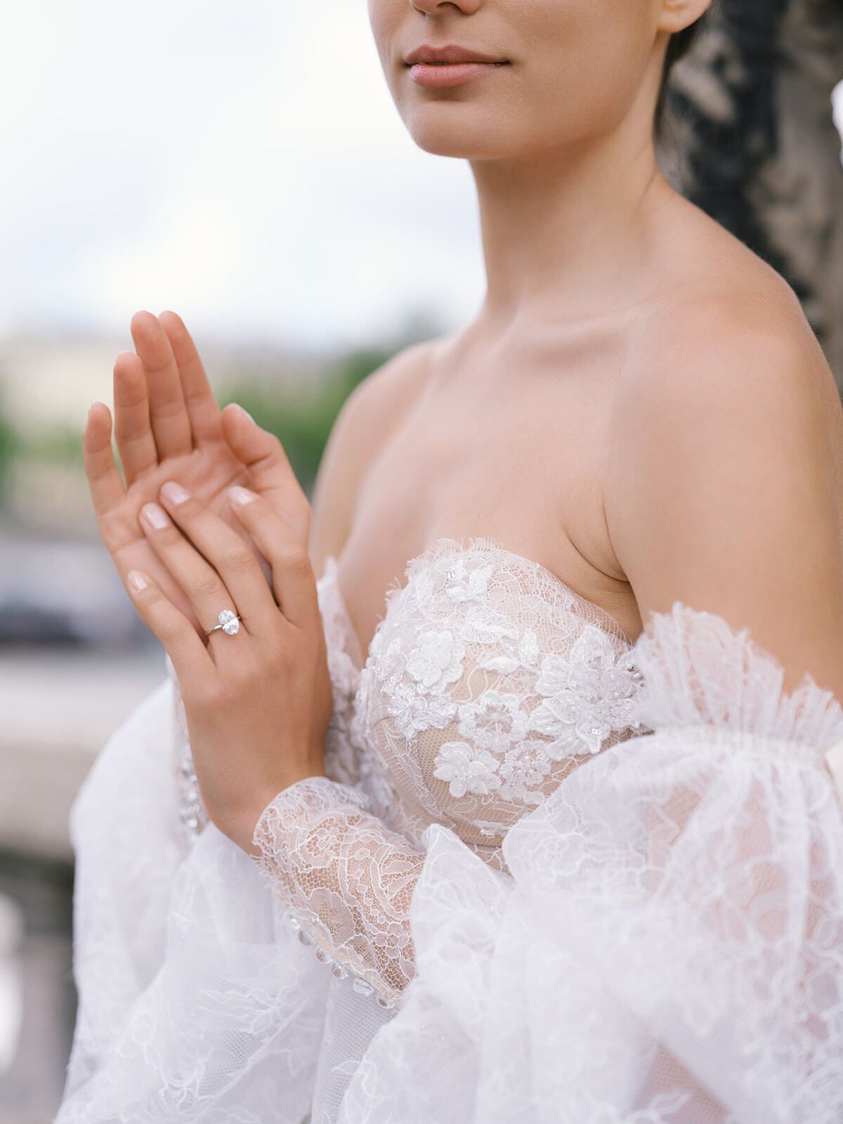 Manos de la novia con anillo de compromiso, detalle del vestido de encaje