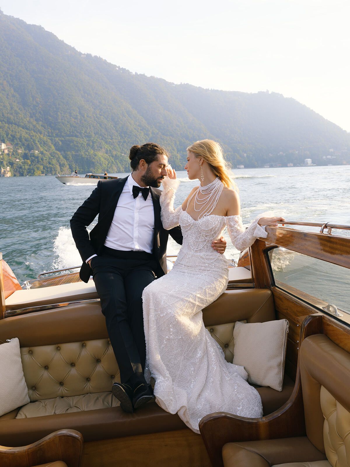 Bride and groom in a vintage wooden boat at sunset, Lake Como