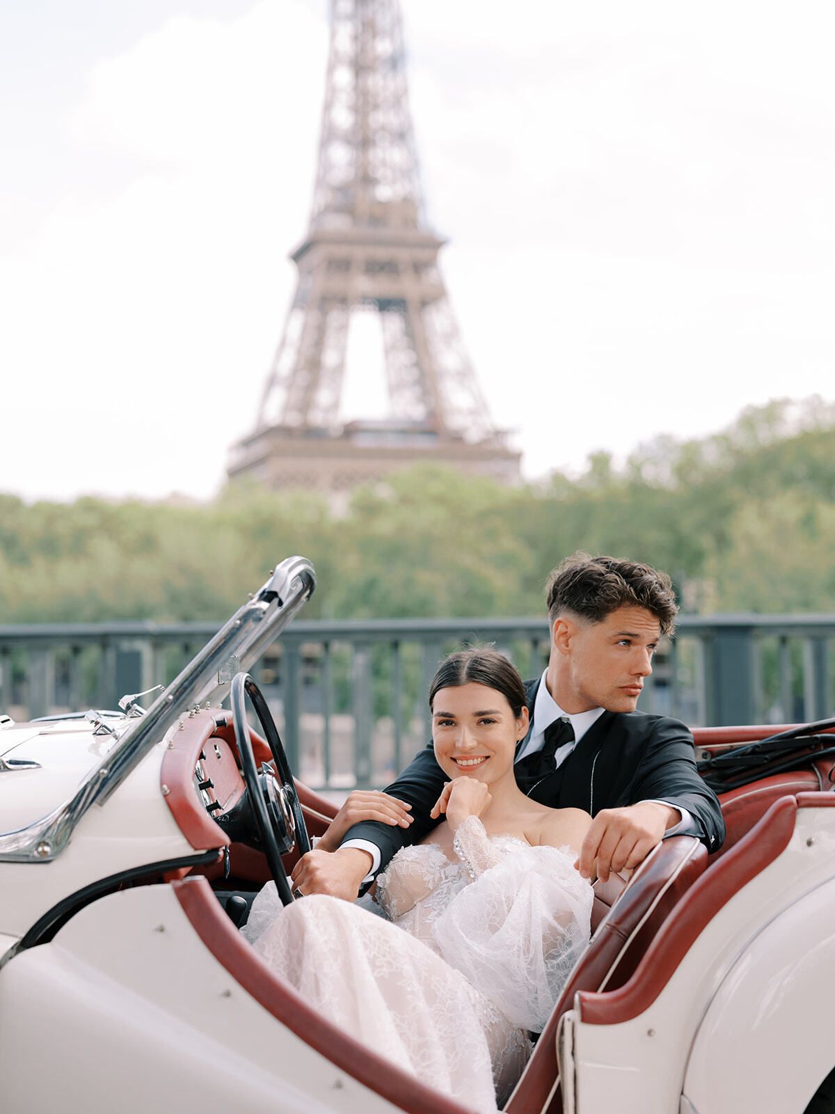 Pareja en un descapotable clásico bajo la Torre Eiffel