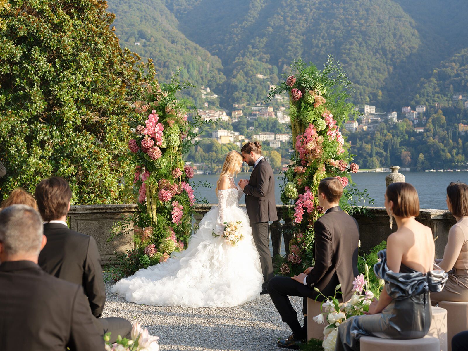 Bride and groom at a floral ceremony arch overlooking Lake Como