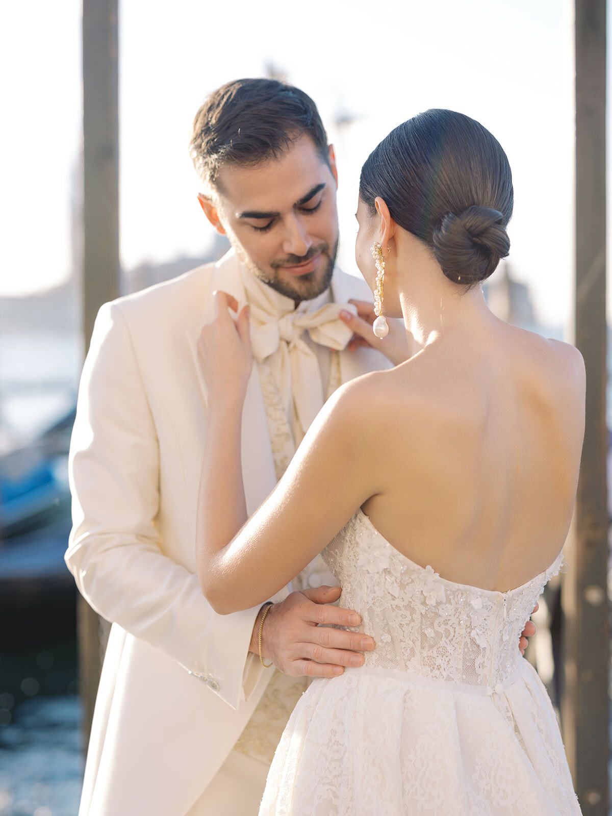 Sposo che sistema il papillon, sposa in abito di pizzo, Venezia