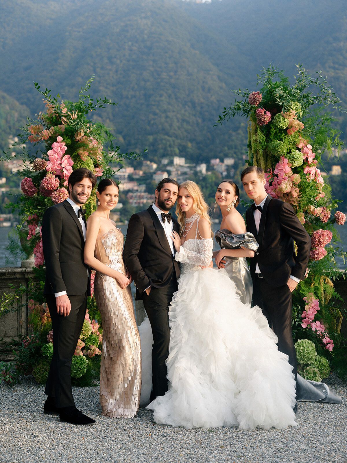 Vanessa y Ricardo con su cortejo bajo arcos florales