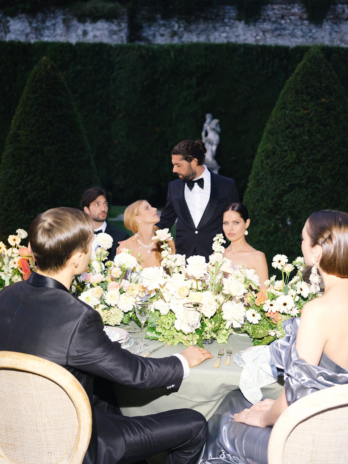 Guests seated at a flower-filled table between hedges, Villa Pizzo