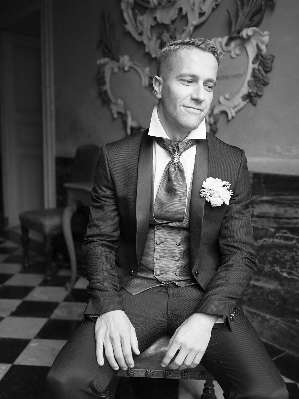 Retrato en blanco y negro de un novio sentado en un salón de la villa
